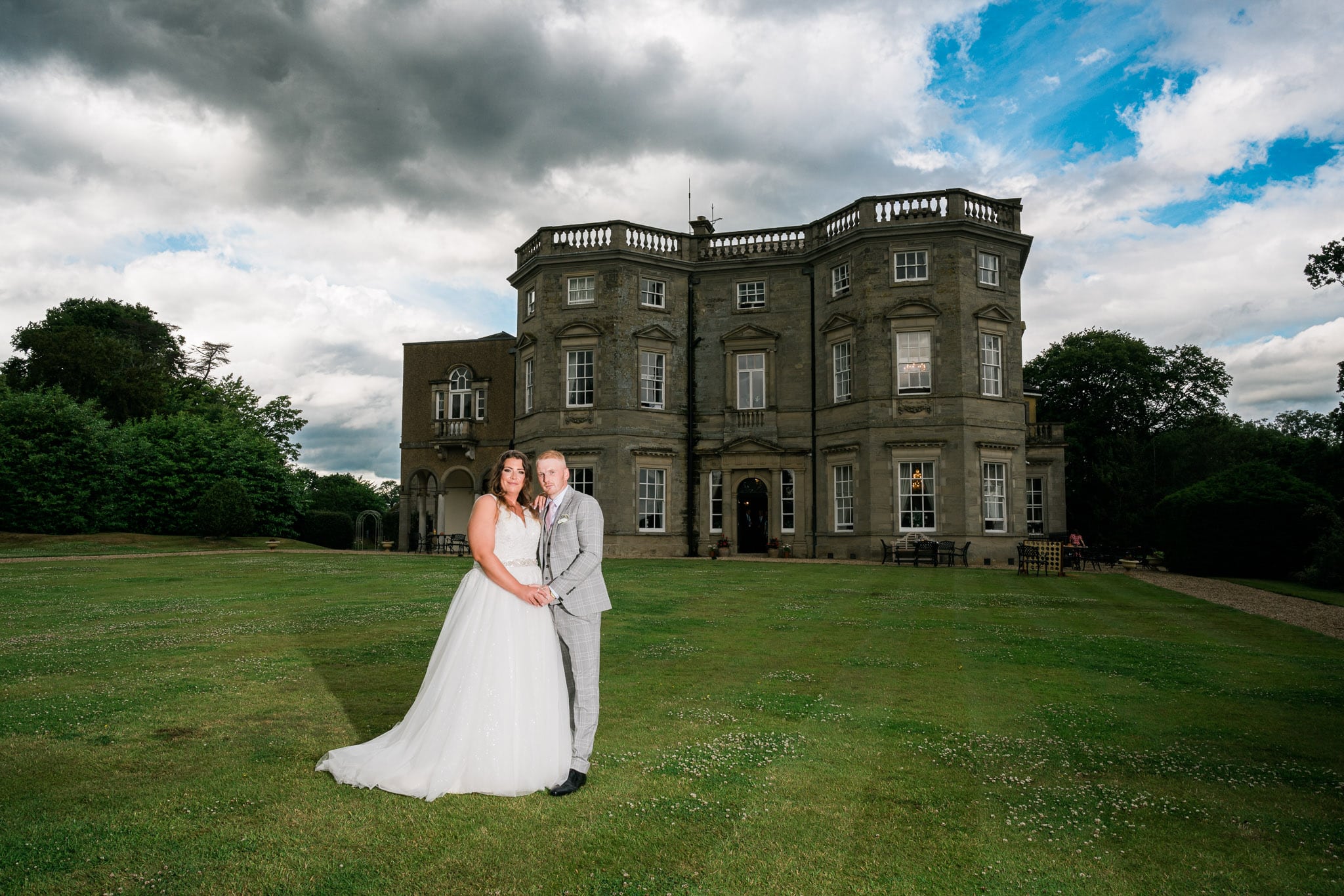 Oliver Kershaw's expert photography skills capture the bride's intricate lace wedding dress and stunning bouquet against the scenic Bourton Hall grounds.