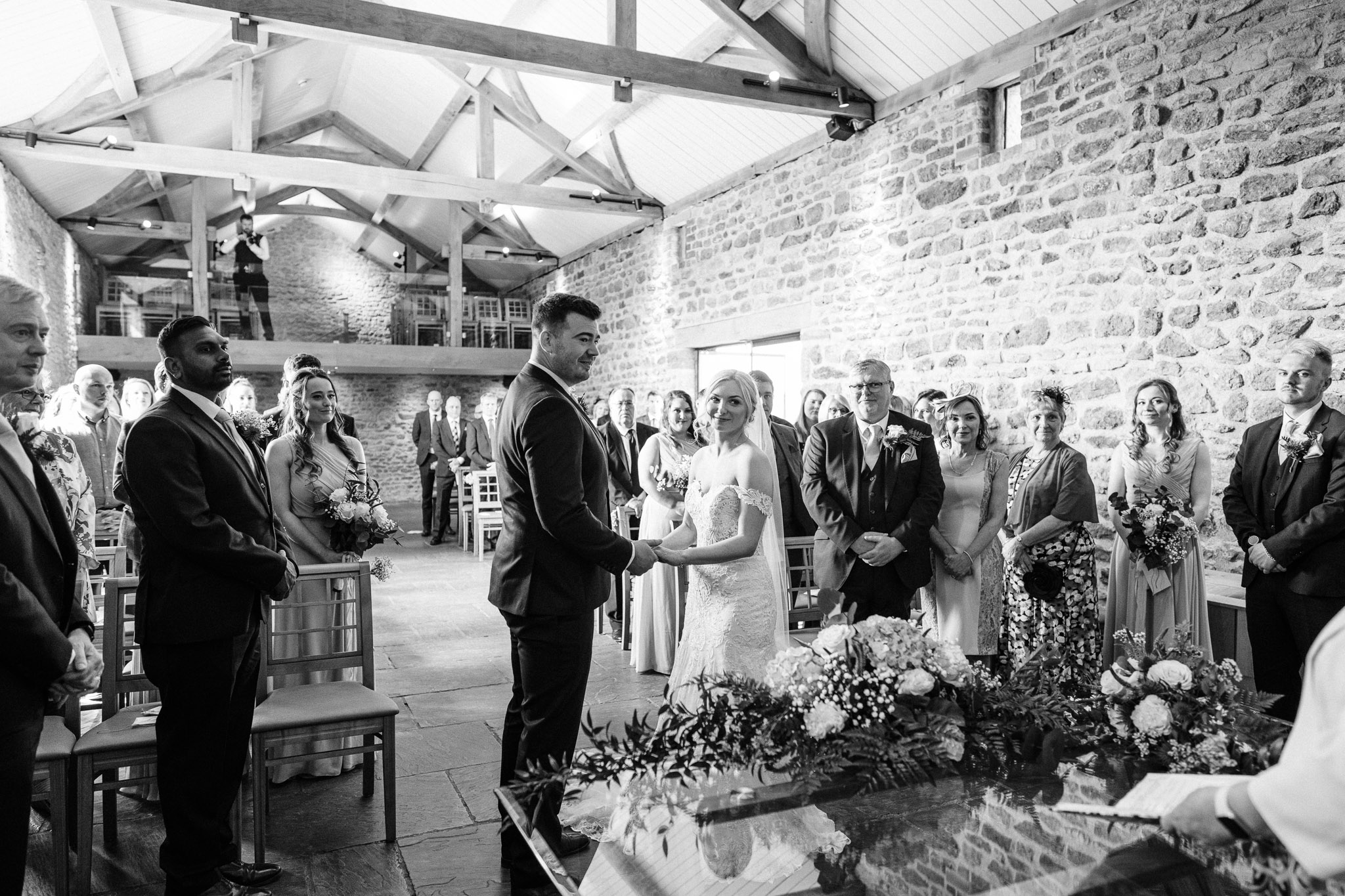 Bride and groom pose in front of a barn at their Dodford Manor wedding, captured beautifully by Oliver Kershaw Photography.
