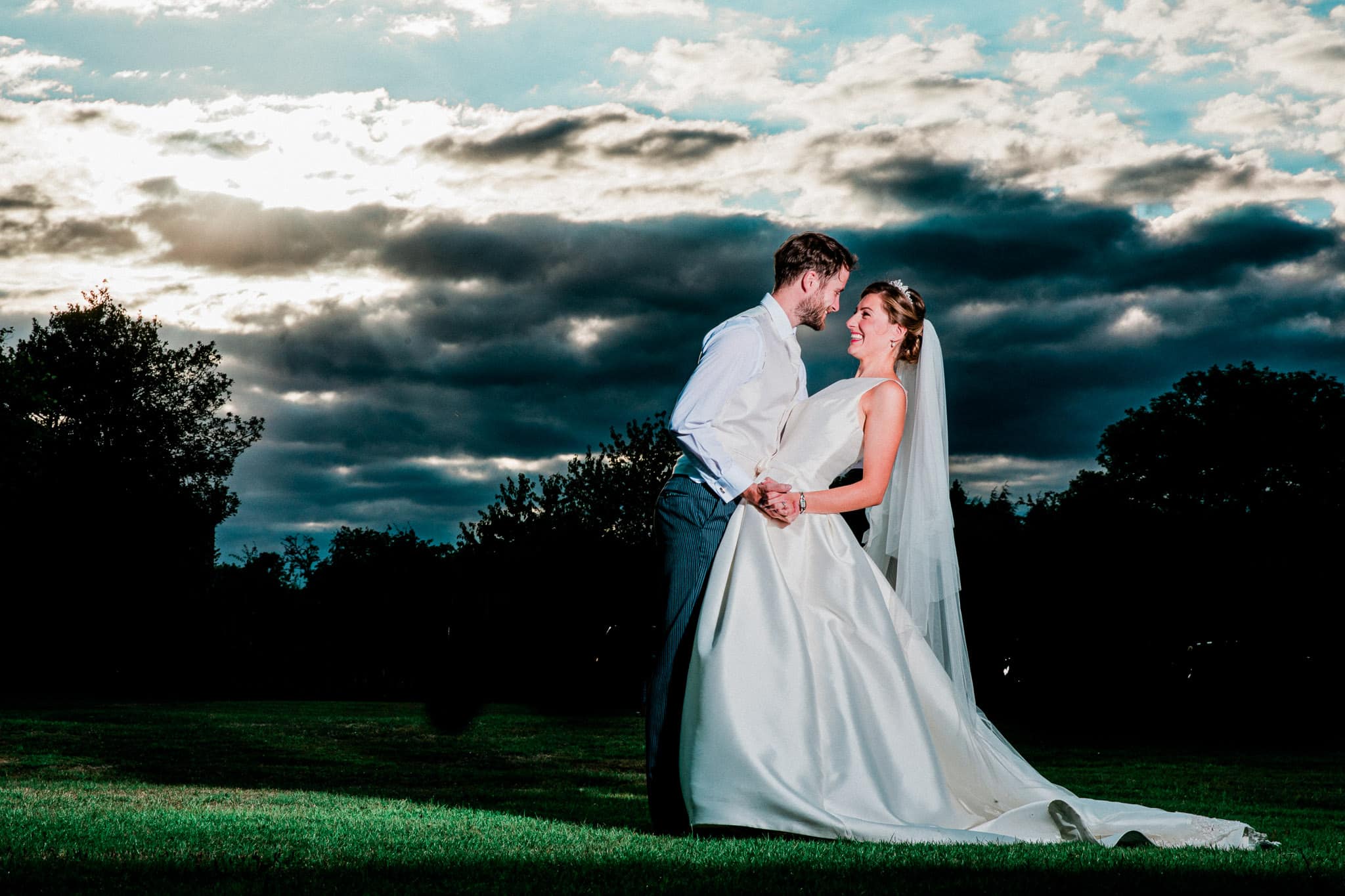 A bride and groom stand in front of a beautiful sunset at The Old Stables Wedding Venue in Leicestershire. The stunning and romantic setting creates a breathtaking atmosphere for the couple to enjoy their special moment together.
