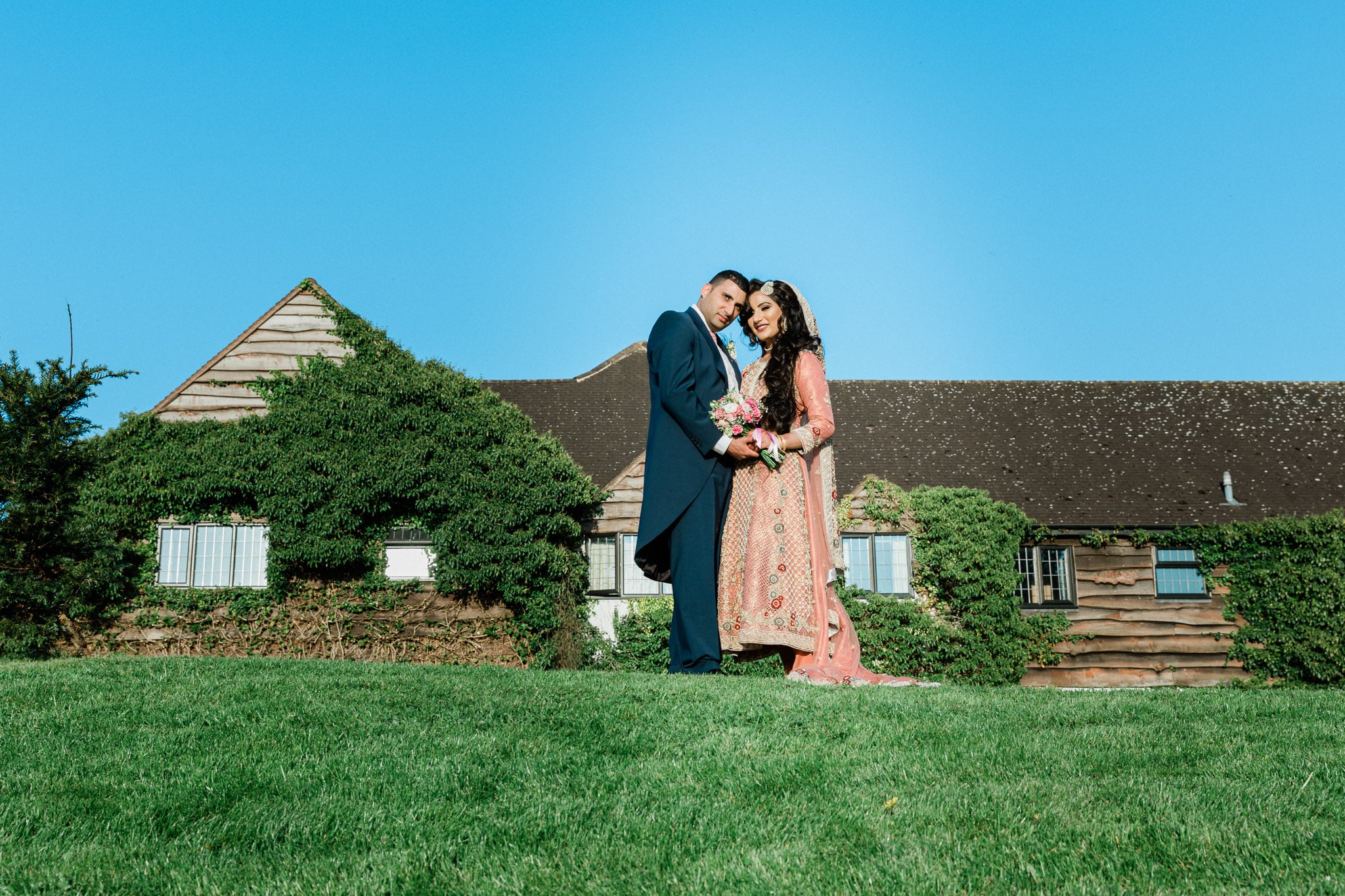 Bride and groom standing on a scenic mound at Sketchley Grange Hotel, Hinckley with a beautiful backdrop.