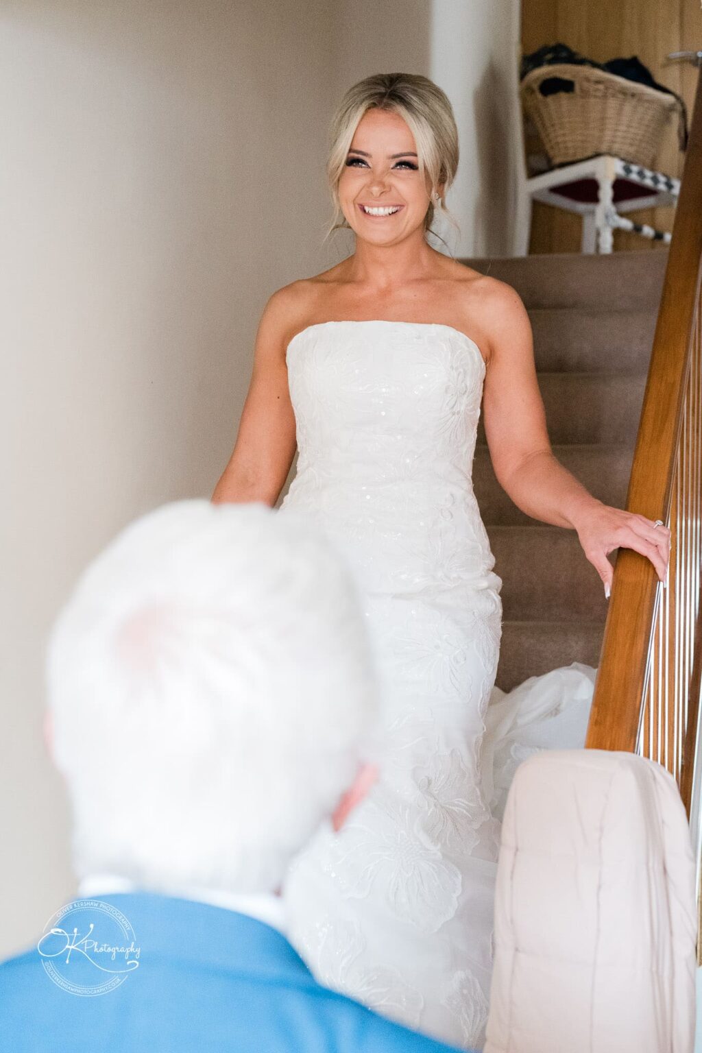 Bride in a white wedding dress smiling while descending stairs.