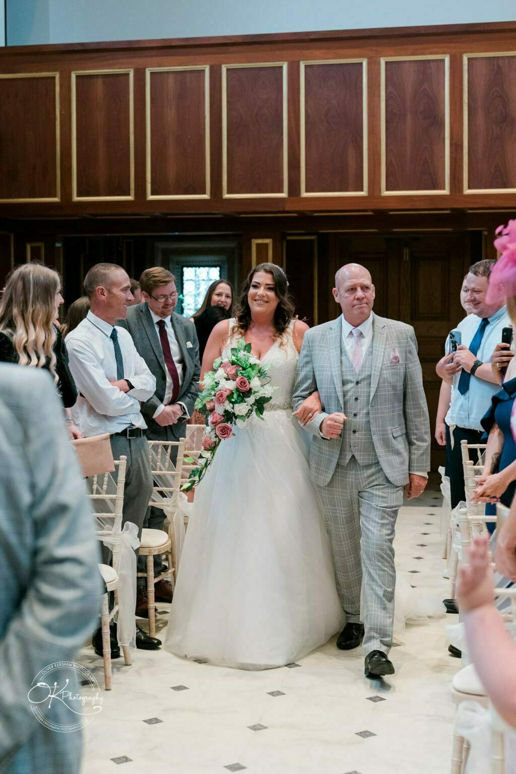 Bride walking down the aisle with her father at Bourton Hall, surrounded by friends and family.