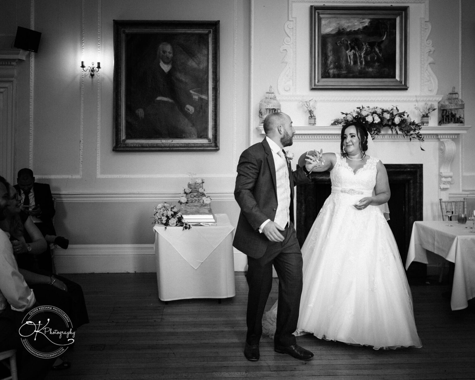 Brooksby Hall Wedding Photography Bride and groom dancing in front of a fireplace beneath two paintings at Brooksby Hall.