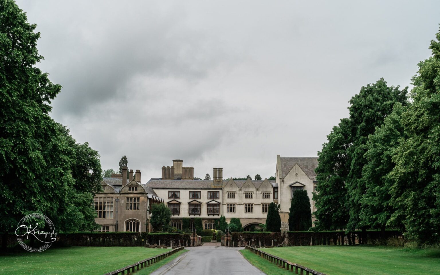 Coombe Abbey Hotel surrounded by lush green trees, with a long driveway leading to the entrance.