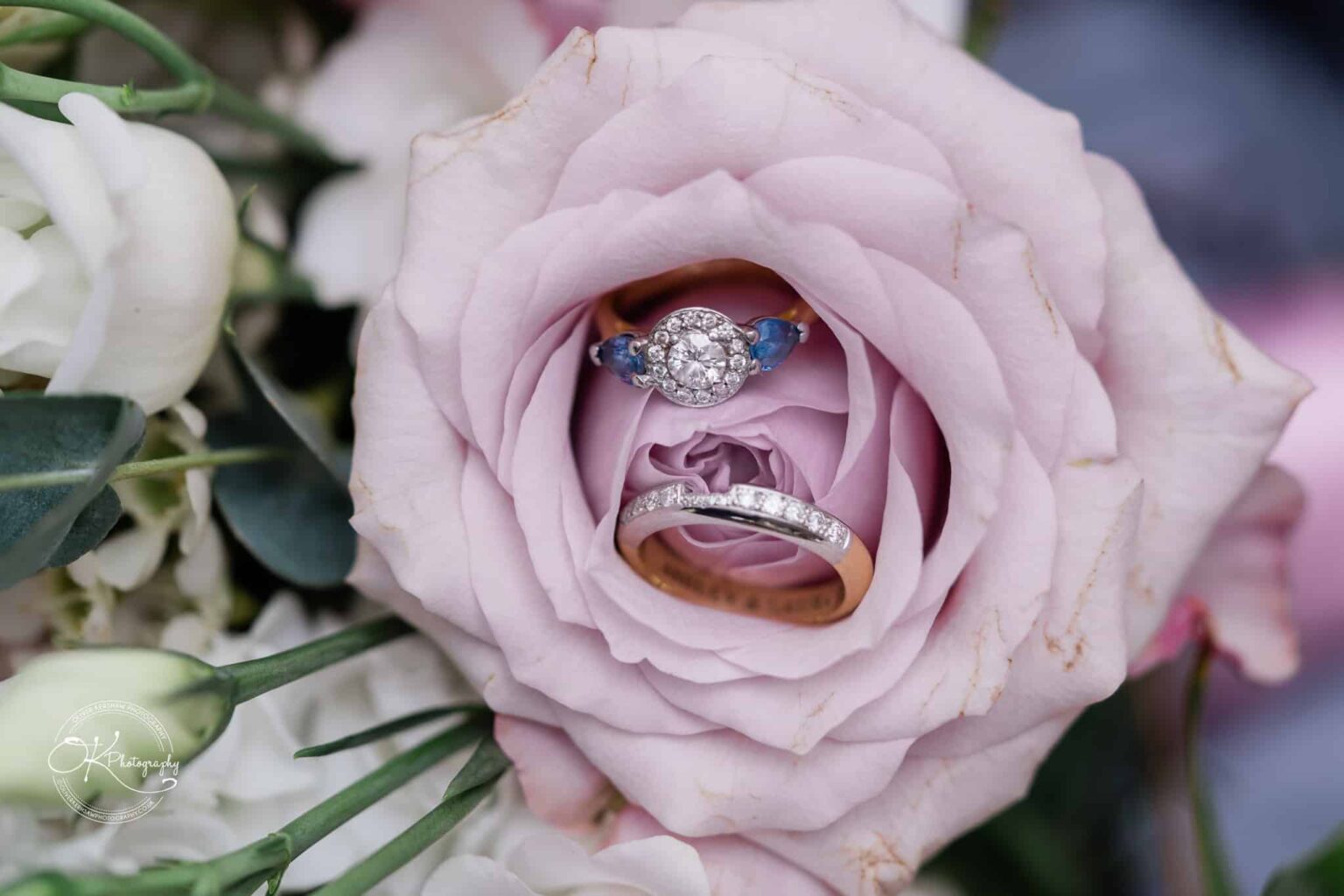 Ettington Park Hotel Wedding Photography Two rings, one with sapphire accents and diamonds and the other with diamonds, placed inside a lavender rose.