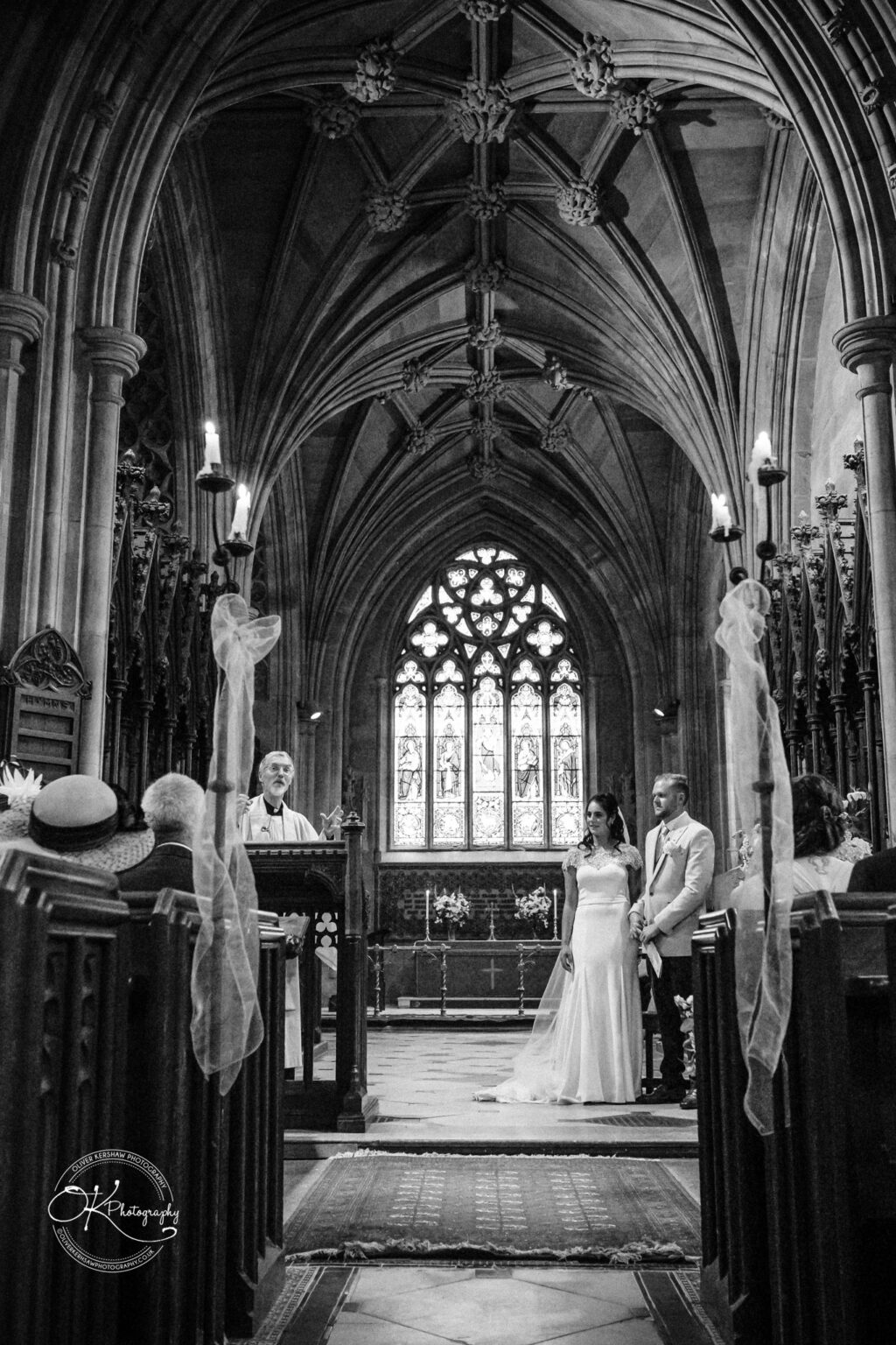 Ettington Park Hotel Wedding Photography A bride and groom stand at the altar in a Gothic-style church during their wedding ceremony.
