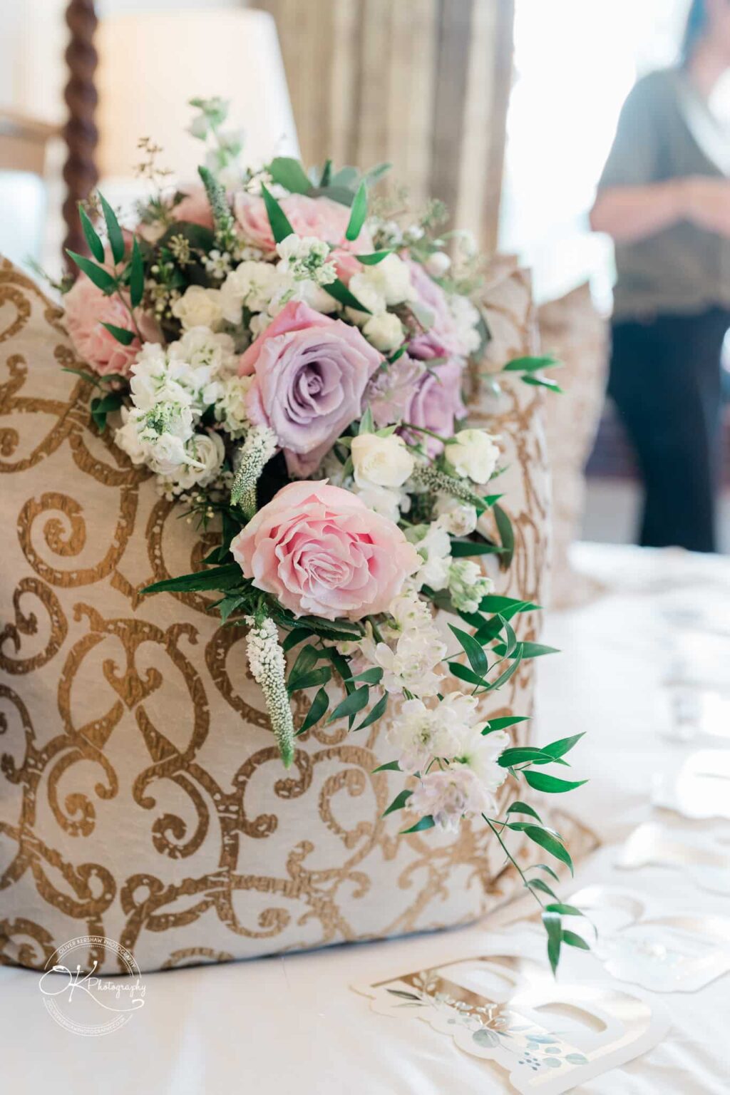 Ettington Park Hotel Wedding Photography Bouquet of pink, purple, and white flowers resting on a decorative cushion with gold patterns.