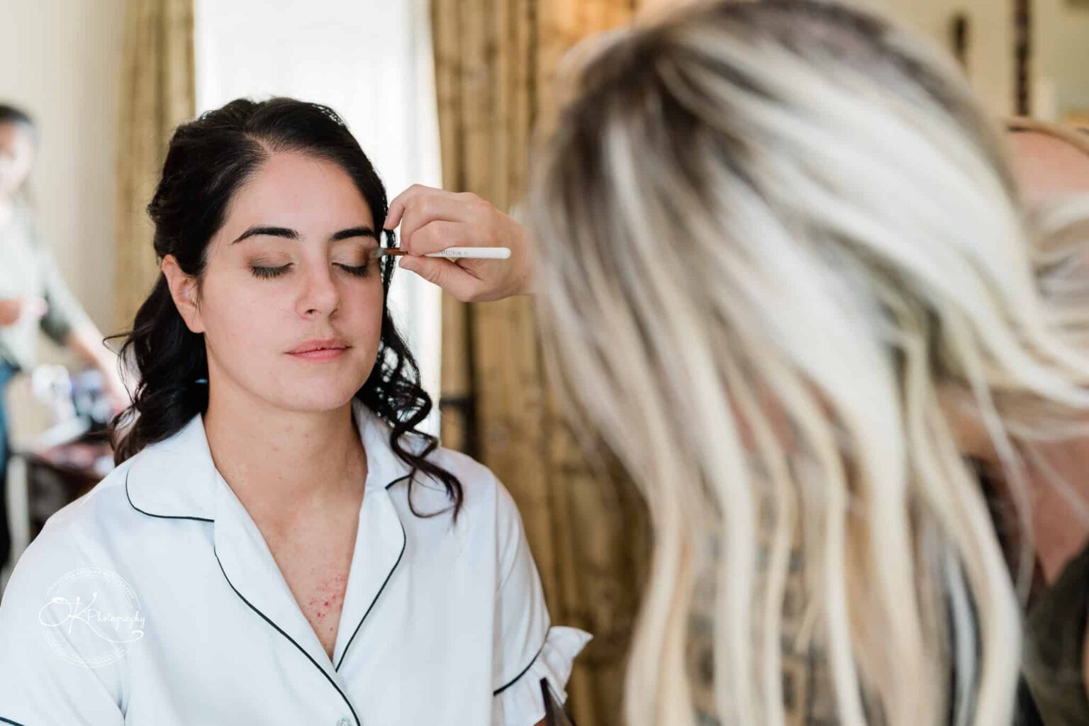 Ettington Park Hotel Wedding Photography A woman with closed eyes getting her makeup done by a makeup artist.