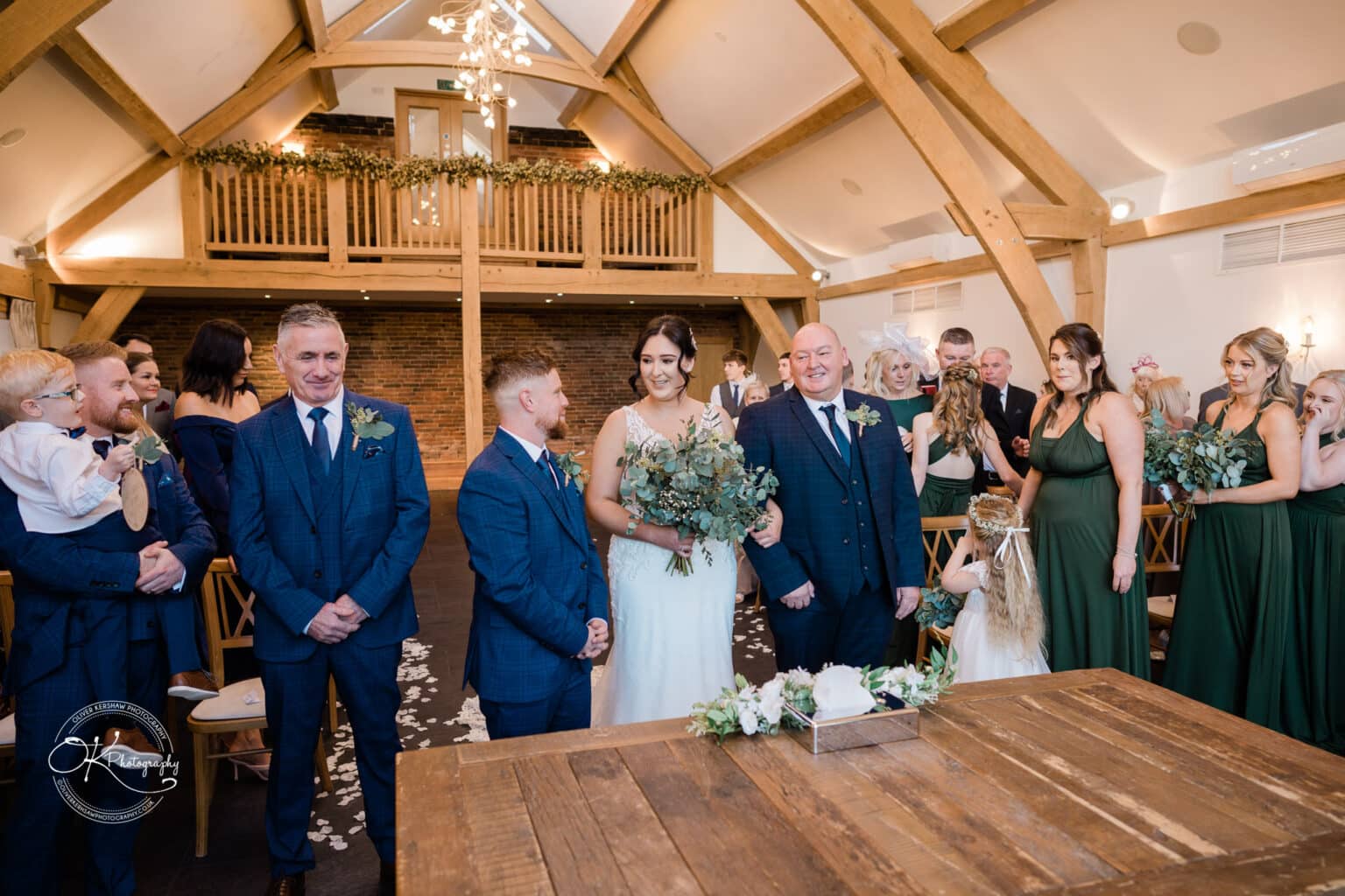 Mythe Barn Wedding photography Bride and groom standing together at the altar, surrounded by family and friends in a rustic barn wedding venue.