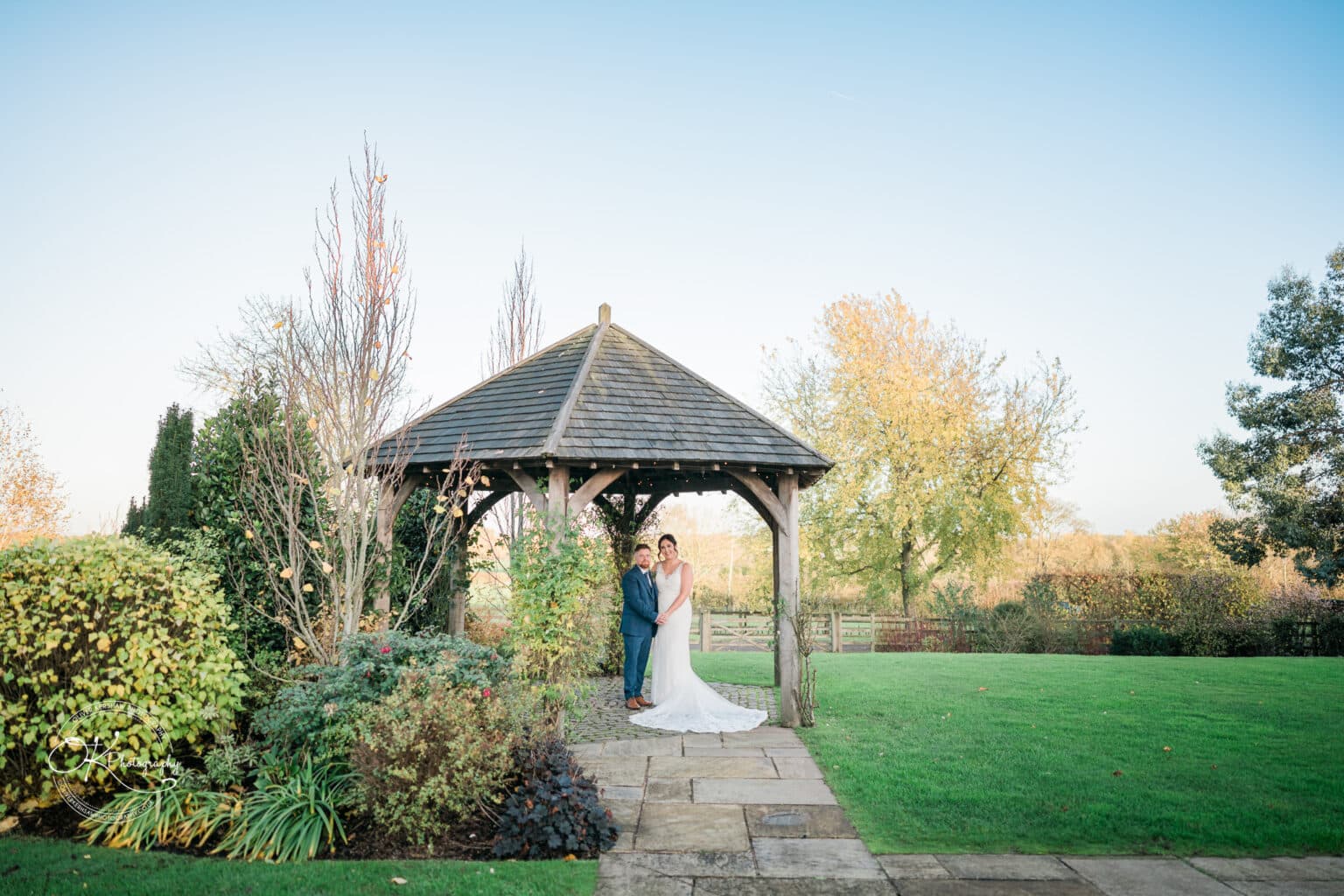 Mythe Barn Wedding photography Bride and groom standing under a wooden gazebo in a garden at Mythe Barn.