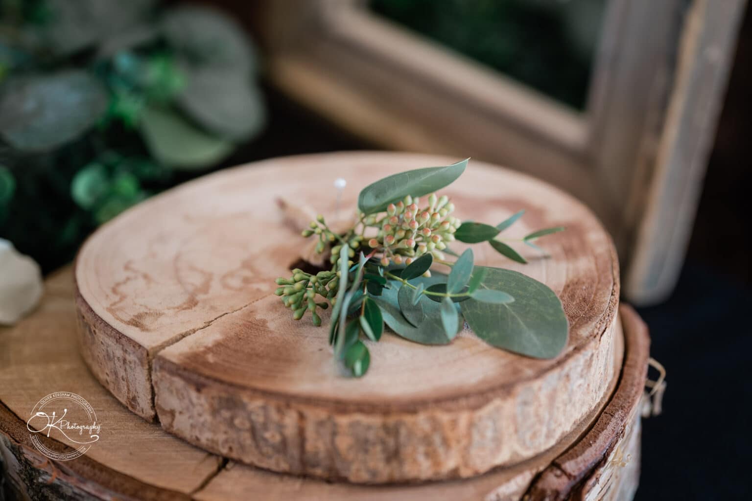 Mythe Barn Wedding photography Greenery and small berries placed on a wooden log slice at a wedding.