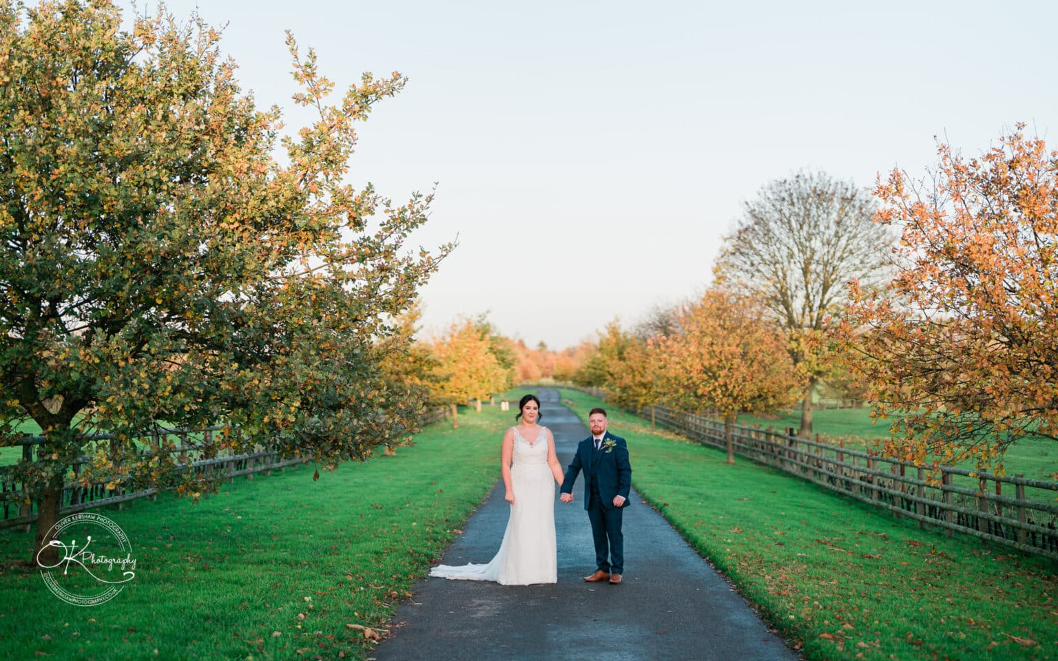 Mythe Barn Wedding photography Bride and groom holding hands on a tree-lined path at Mythe Barn.