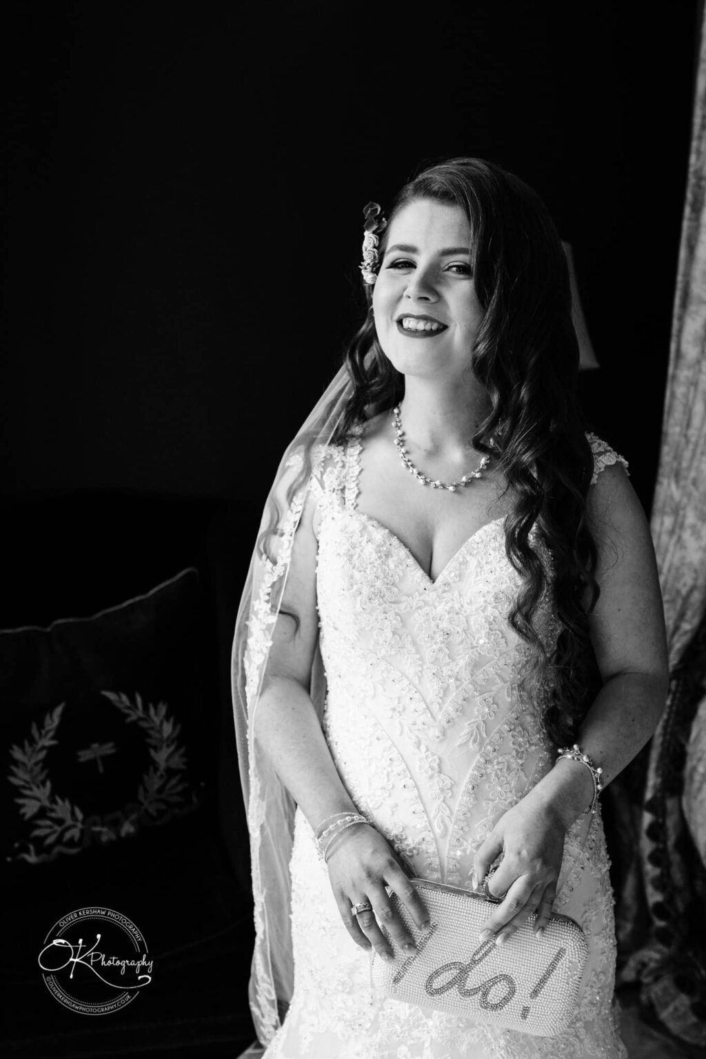 Prestwold Hall Wedding Photography Black and white photo of a smiling bride in a wedding dress holding a purse that says "I do!"