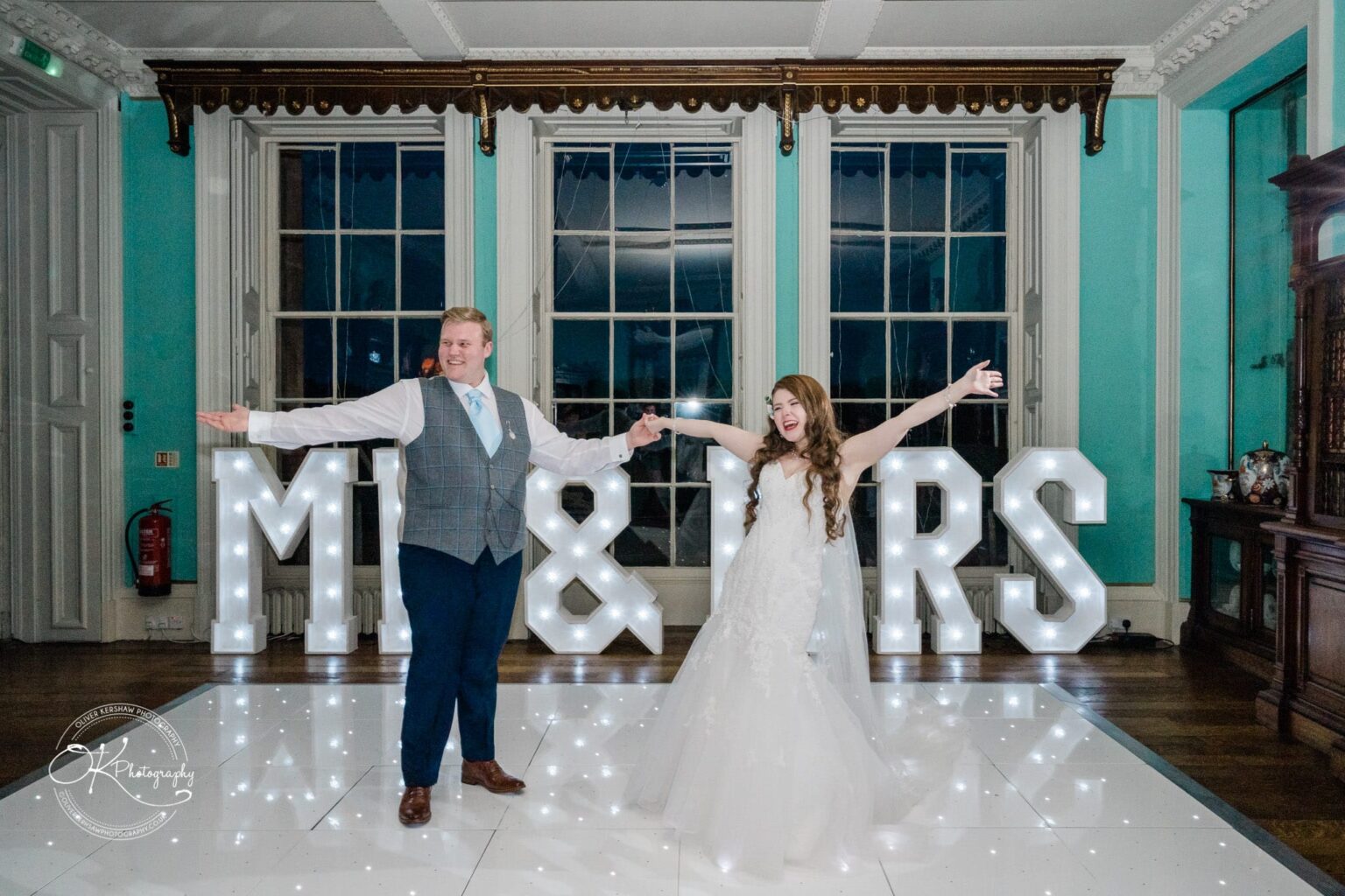 Prestwold Hall Wedding Photography A newlywed couple dancing in front of large, illuminated "Mr & Mrs" letters at Prestwold Hall.