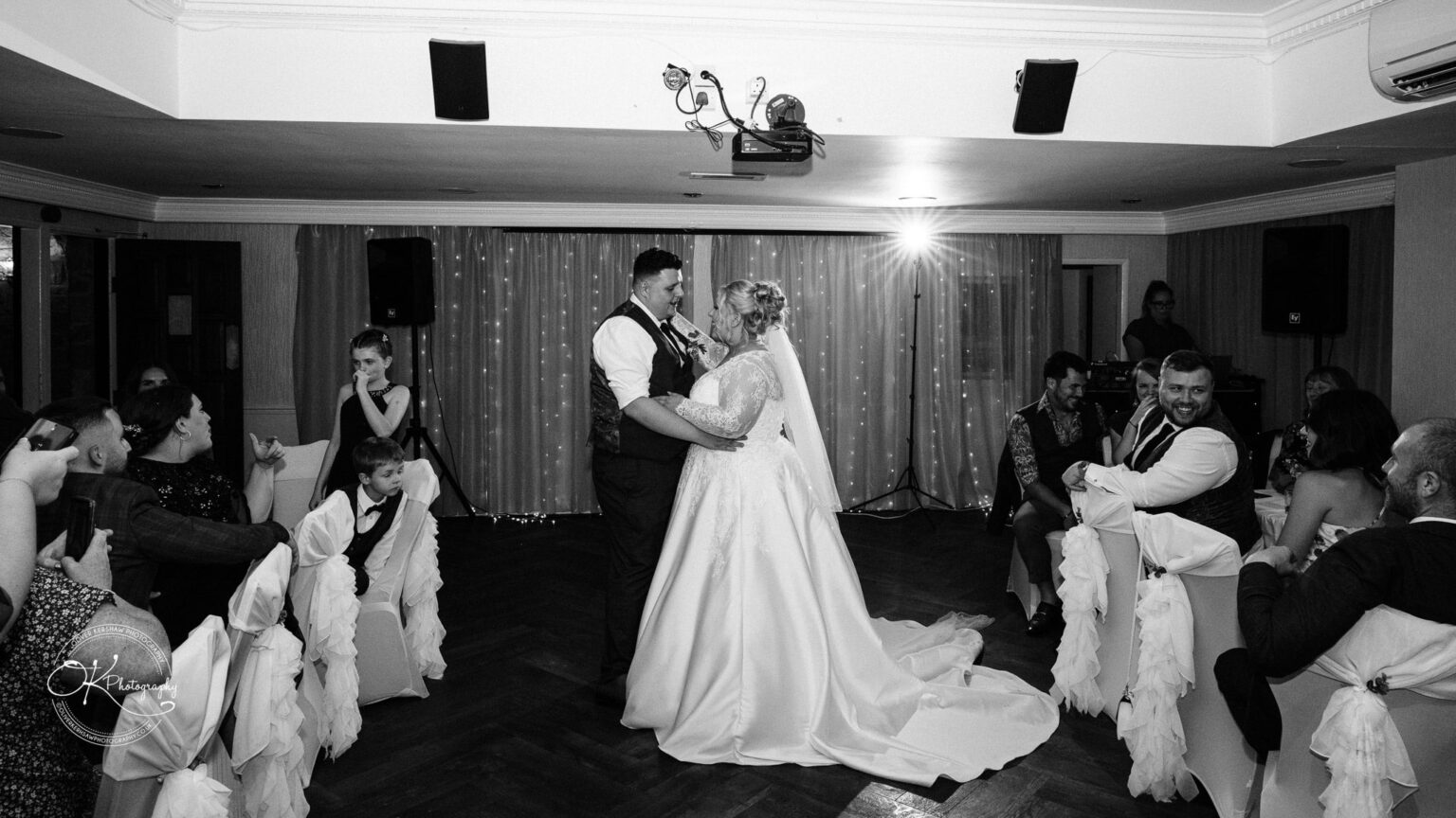 Santos Higham Farm Wedding Photography A bride and groom dance together while guests watch and children sit on chairs at a wedding reception.