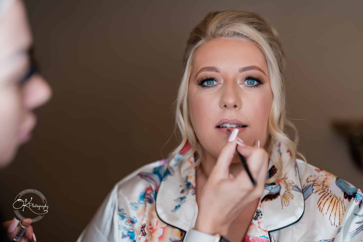 Santos Higham Farm Wedding Photography A woman having her makeup applied, with focus on her face and the makeup brush.