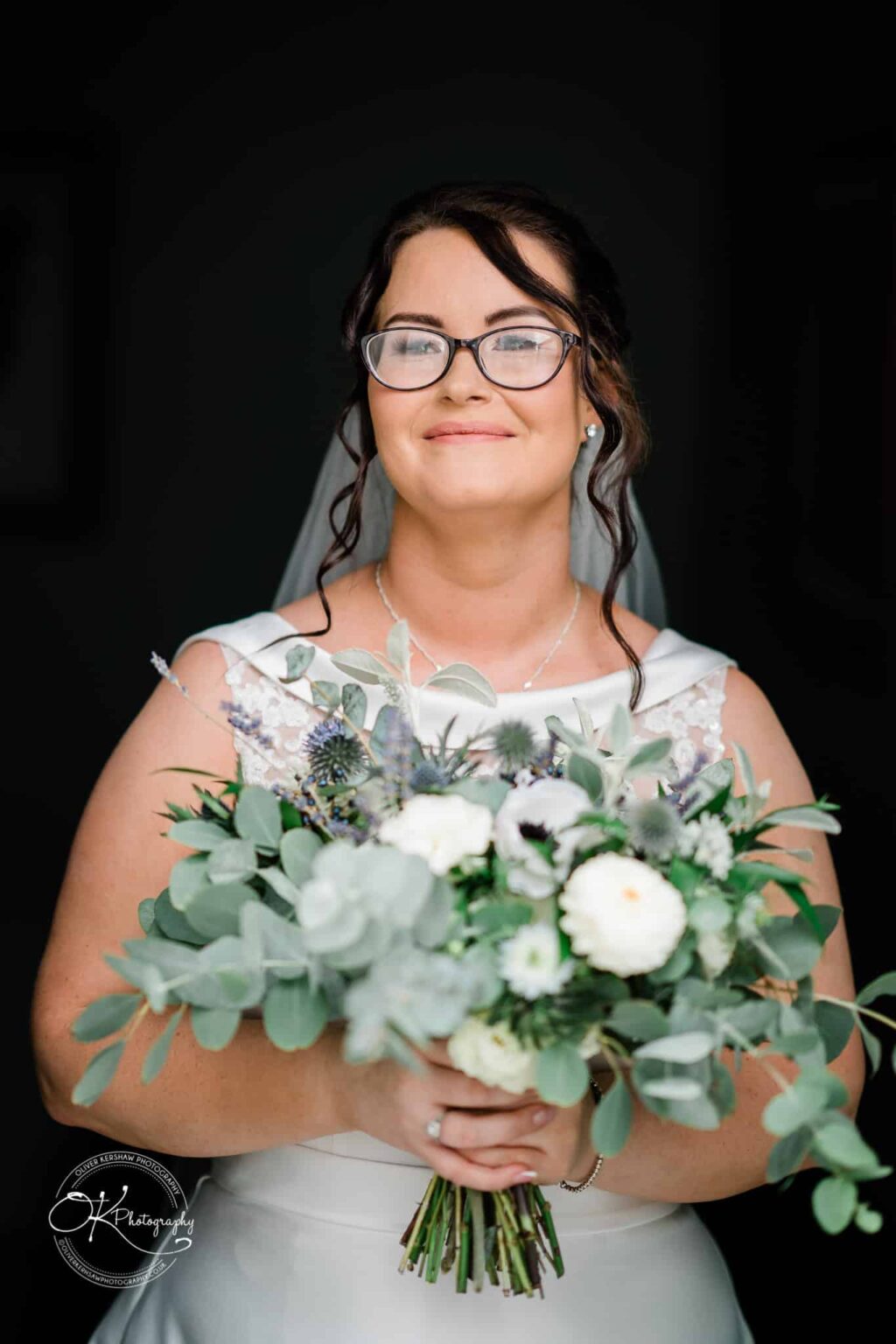 Shearsby Bath Wedding Photography Bride with glasses holding a bouquet of flowers, smiling at the camera.