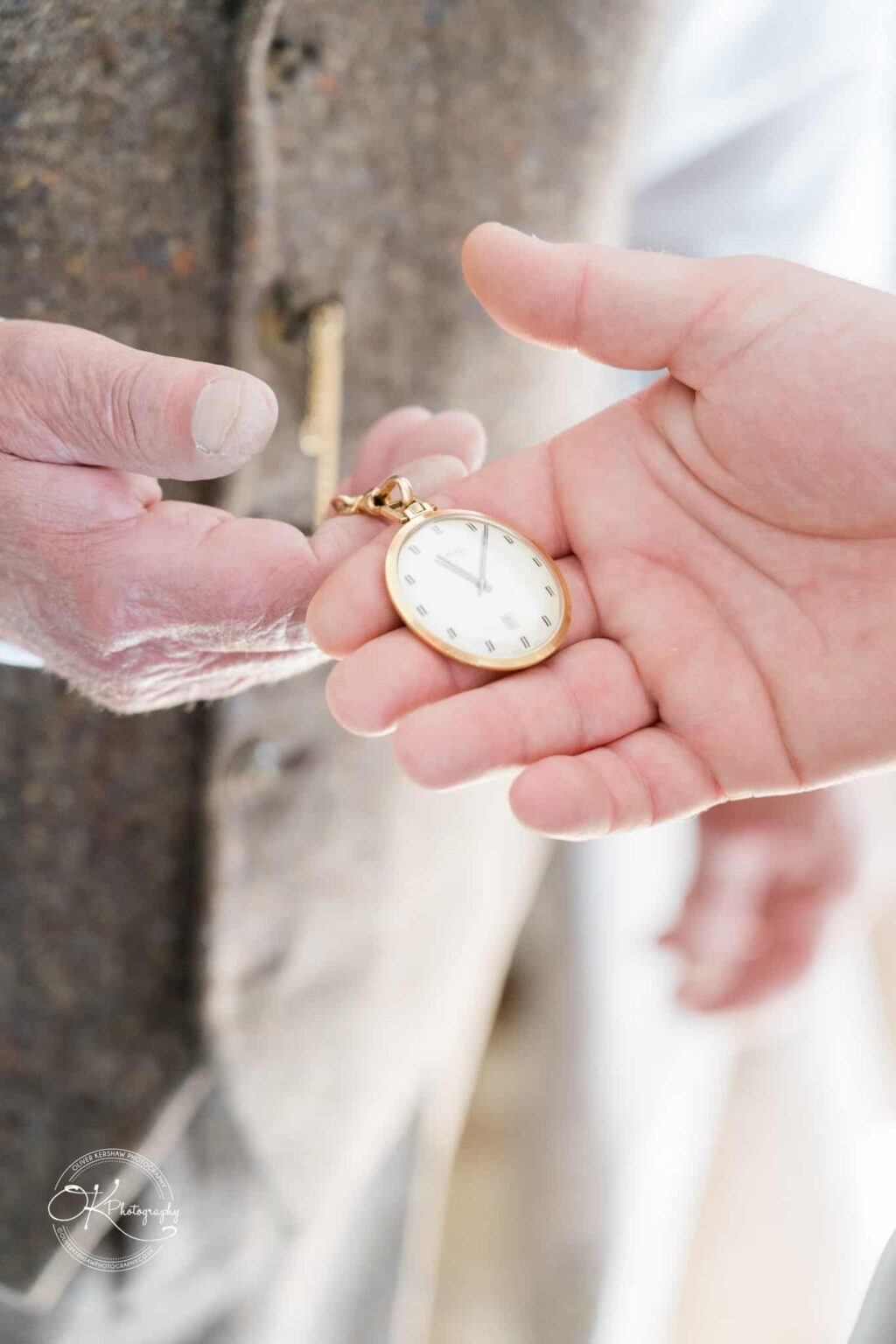 Close-up of two hands exchanging a gold pocket watch.