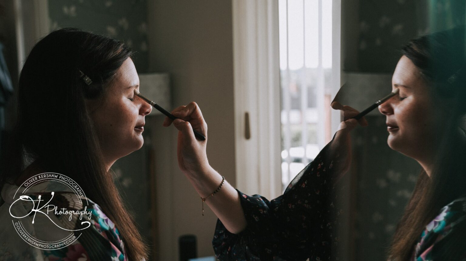 A woman getting her makeup done with a reflection in the mirror, taken by Oliver Kershaw Photography.