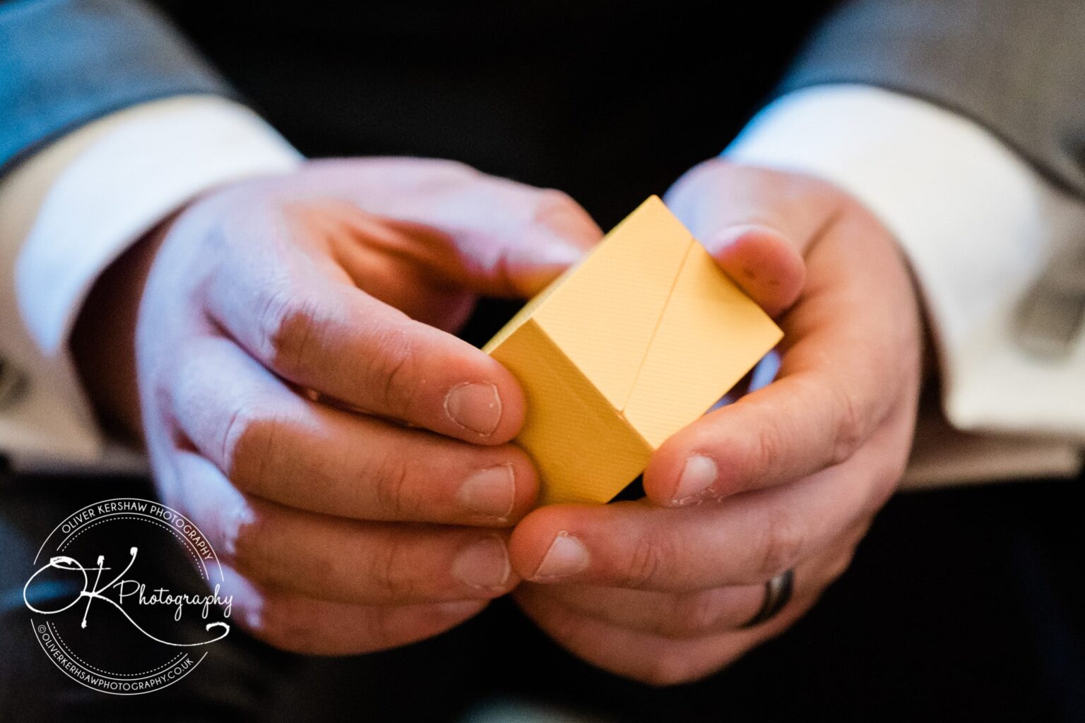 Close-up of a man's hands holding a small yellow gift box.