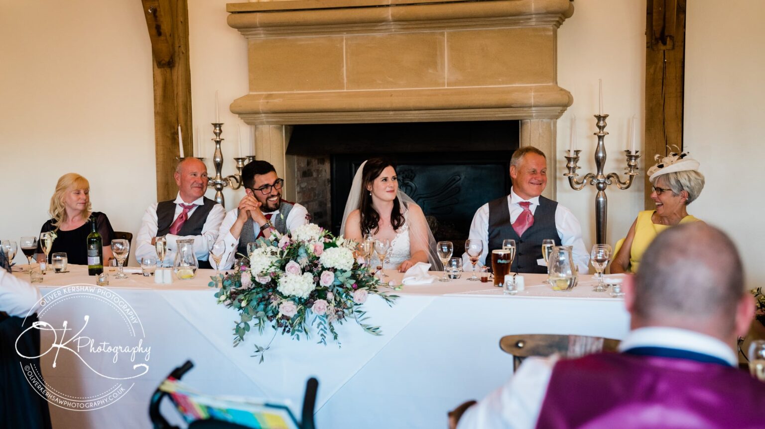 Bridal party seated at a wedding reception table, sharing a joyful moment at Swancar Farm.
