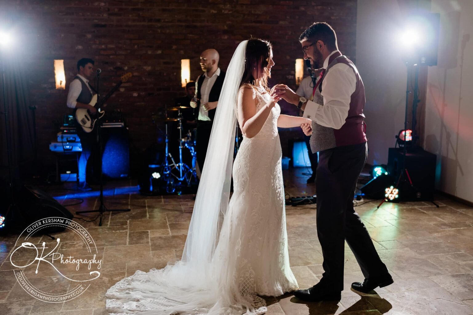 Bride and groom dancing at their wedding reception, with a live band performing in the background.