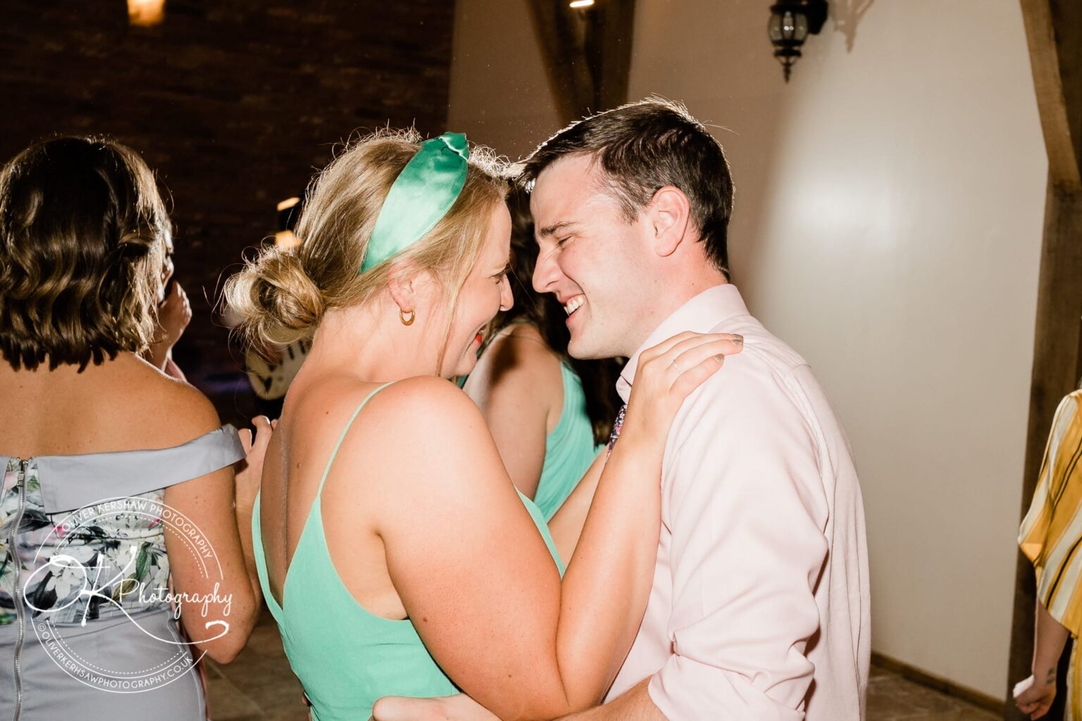 A couple dancing closely together, smiling, at a wedding reception.