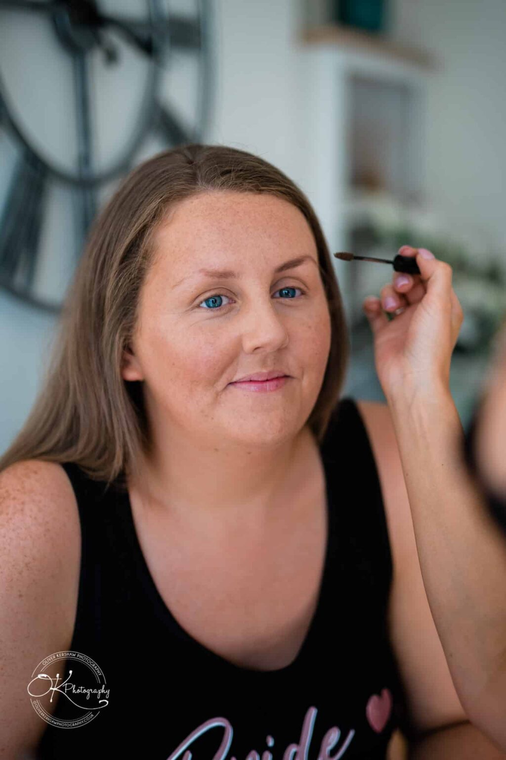 Woman applying mascara while looking into a mirror.