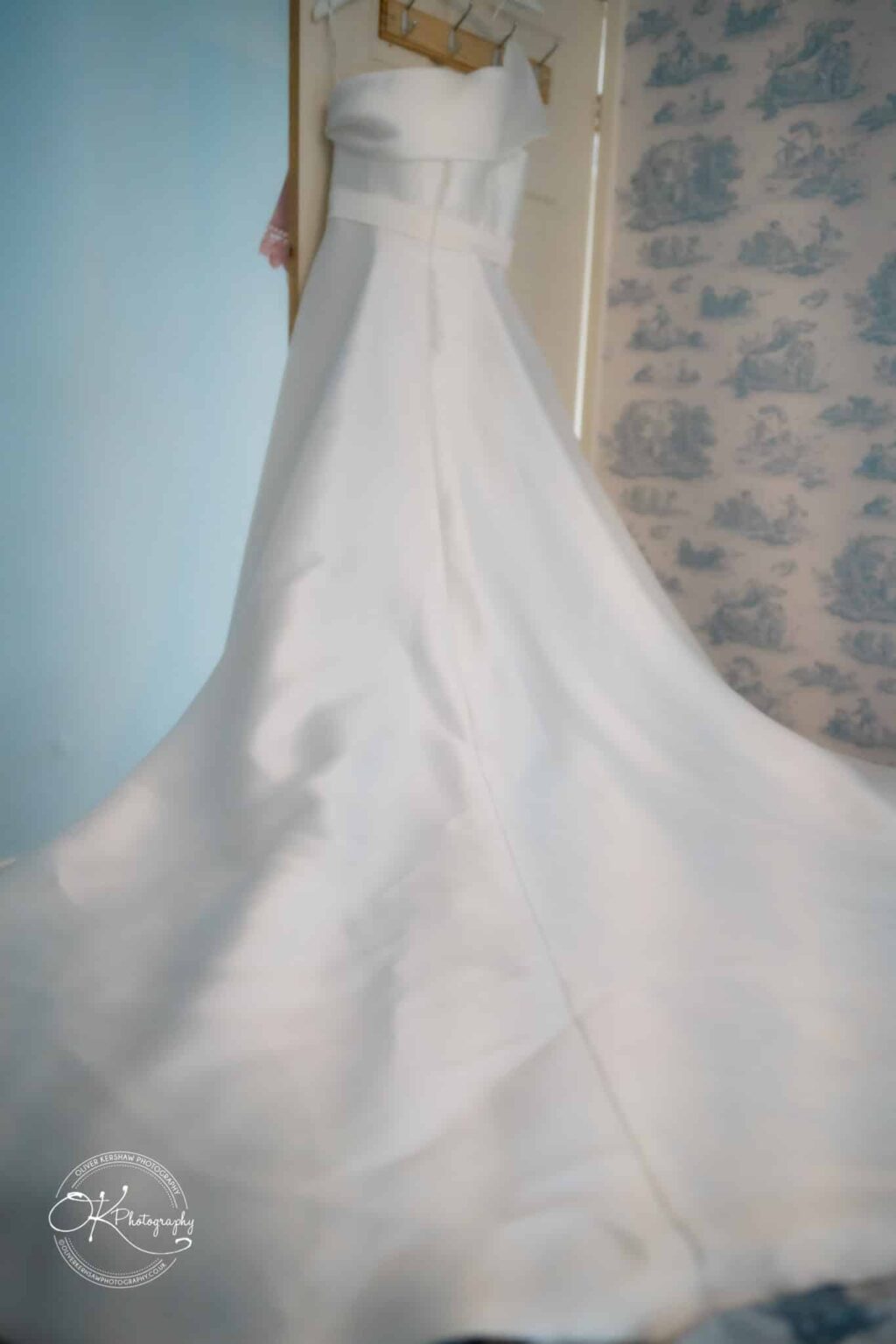 Strapless white wedding dress hanging on a door.