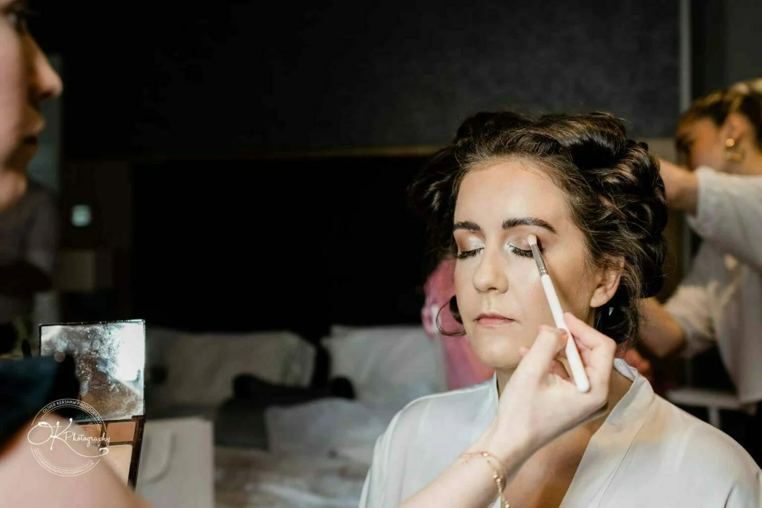 Warwick House Wedding Photography A bride has her makeup applied with a brush on her eyelid, preparing for her wedding.