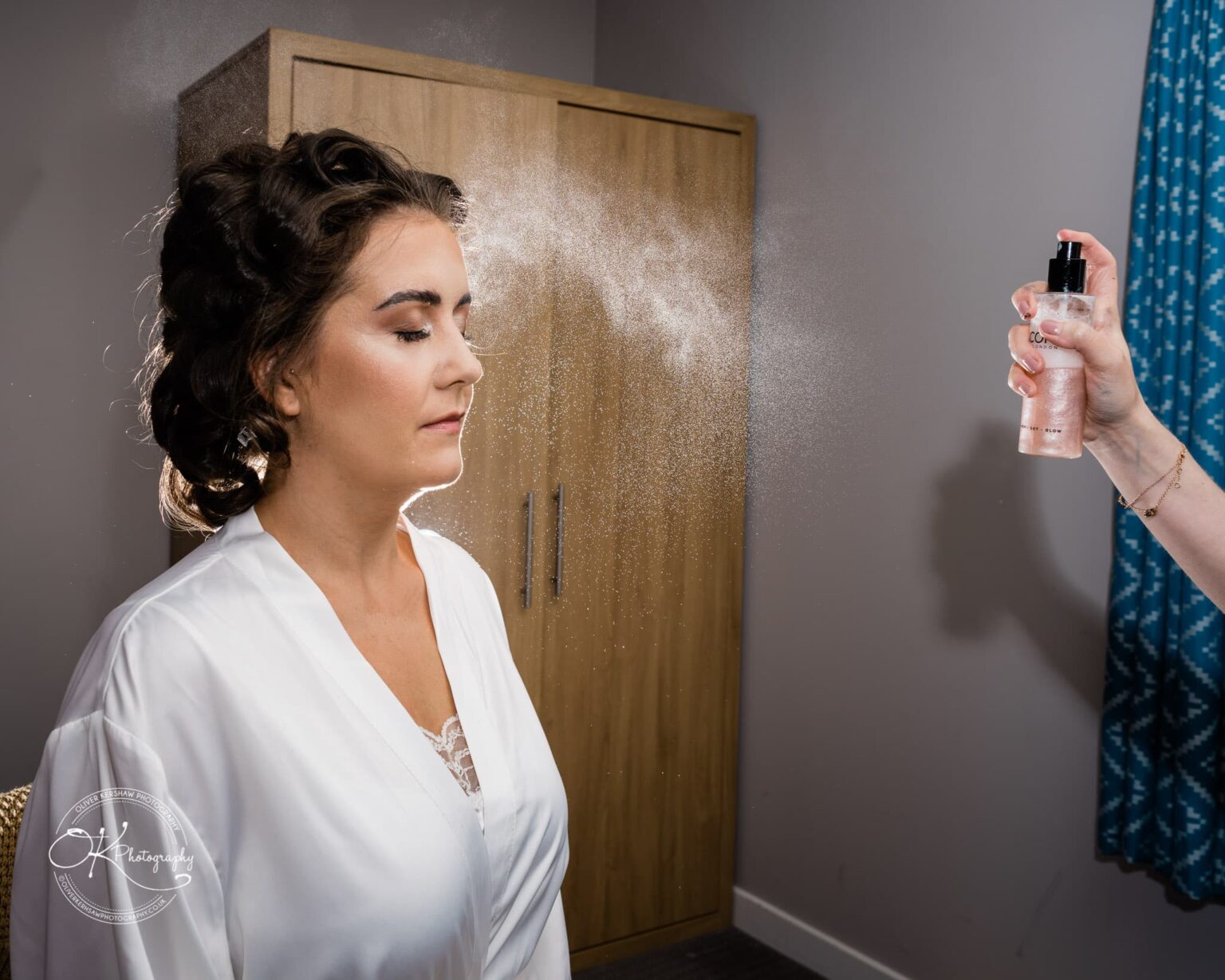Warwick House Wedding Photography A woman in a white robe being sprayed with a mist by another person.