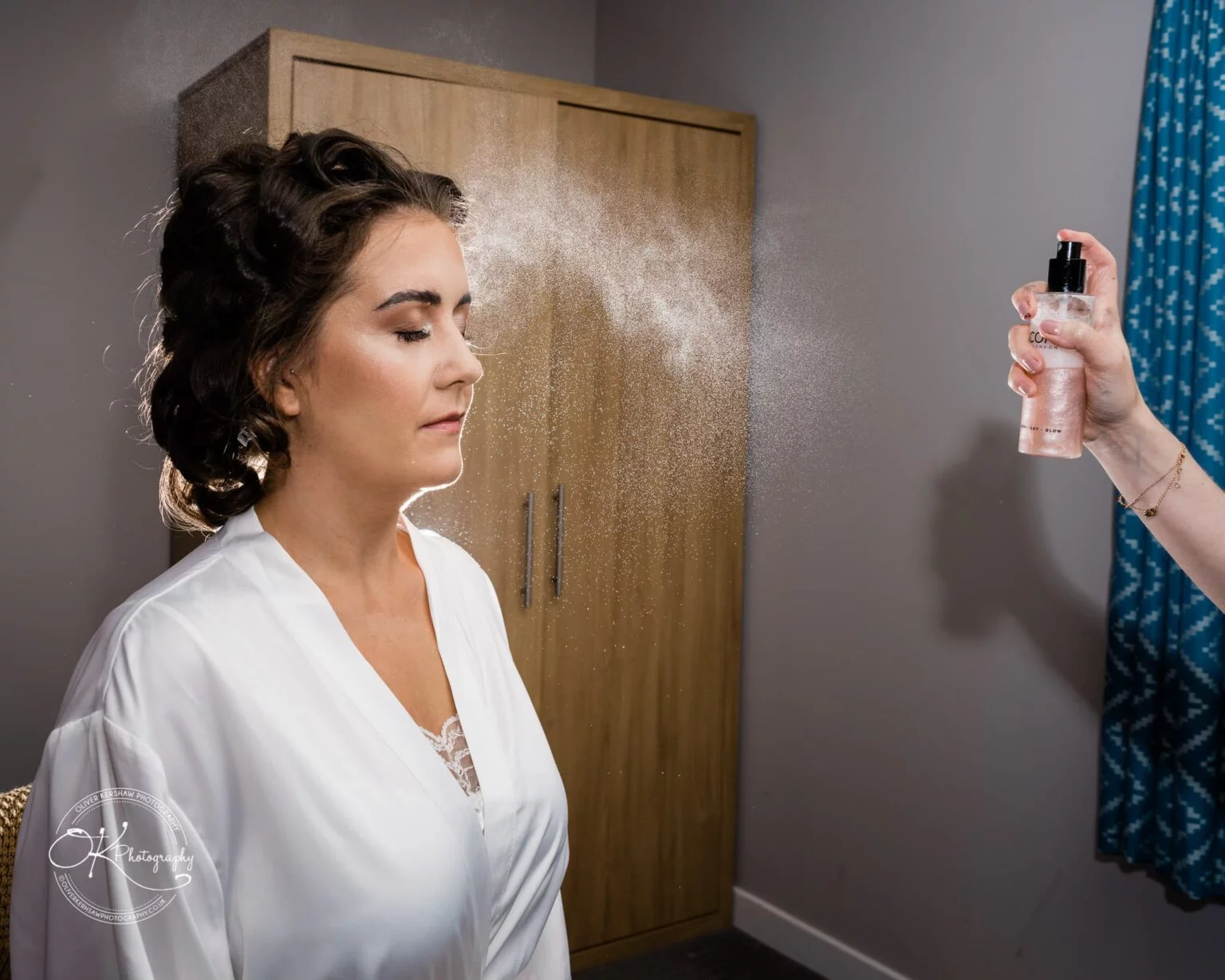 Warwick House Wedding Photography A woman in a white robe being sprayed with a mist by another person.