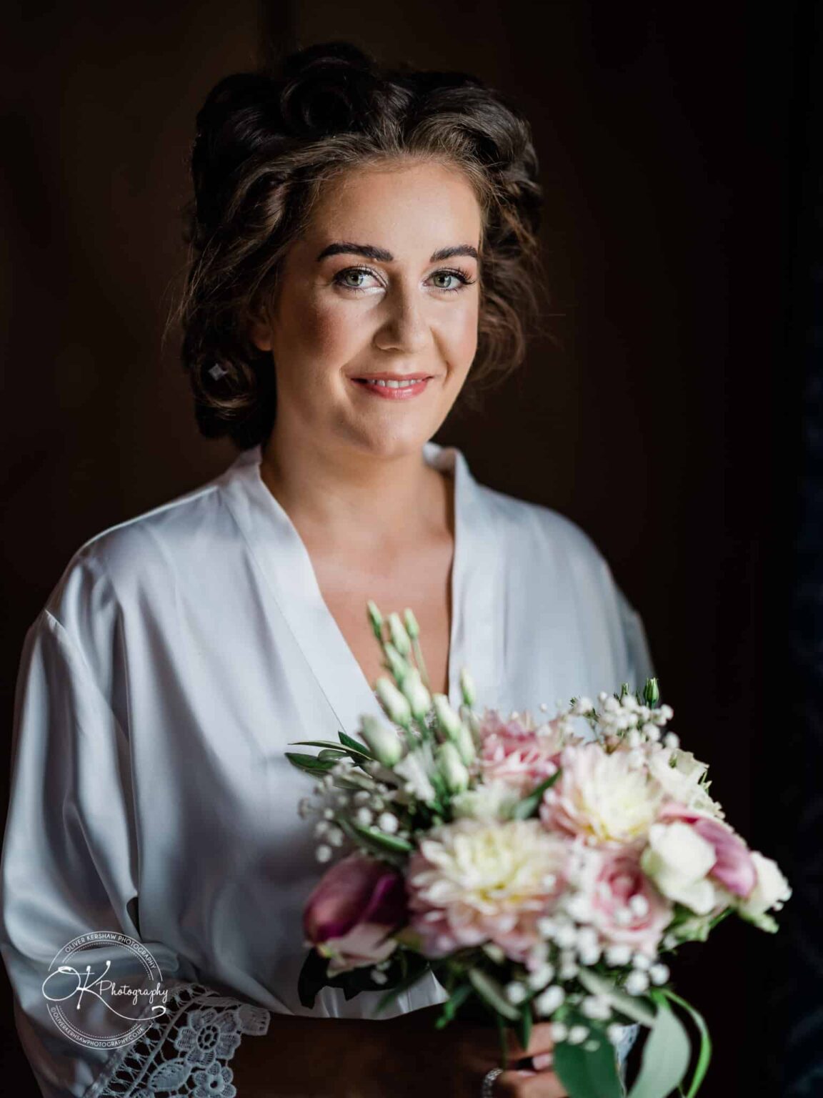 Warwick House Wedding Photography Bride in white robe holding a bouquet of flowers, smiling at the camera.