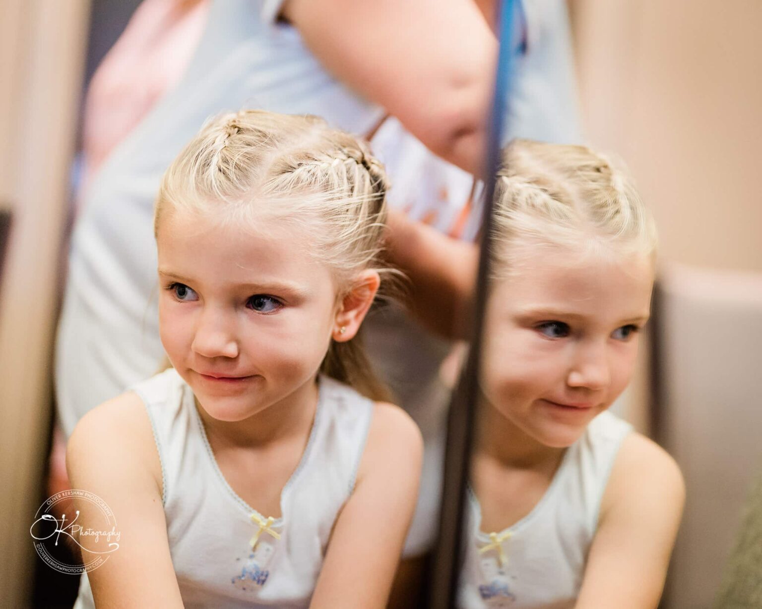 Wedding photography The Embankment A young girl with braided hair looking at her reflection in a mirror.