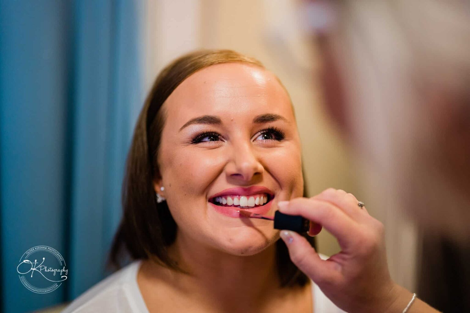 Wedding photography The Embankment A woman smiling while having lipstick applied.