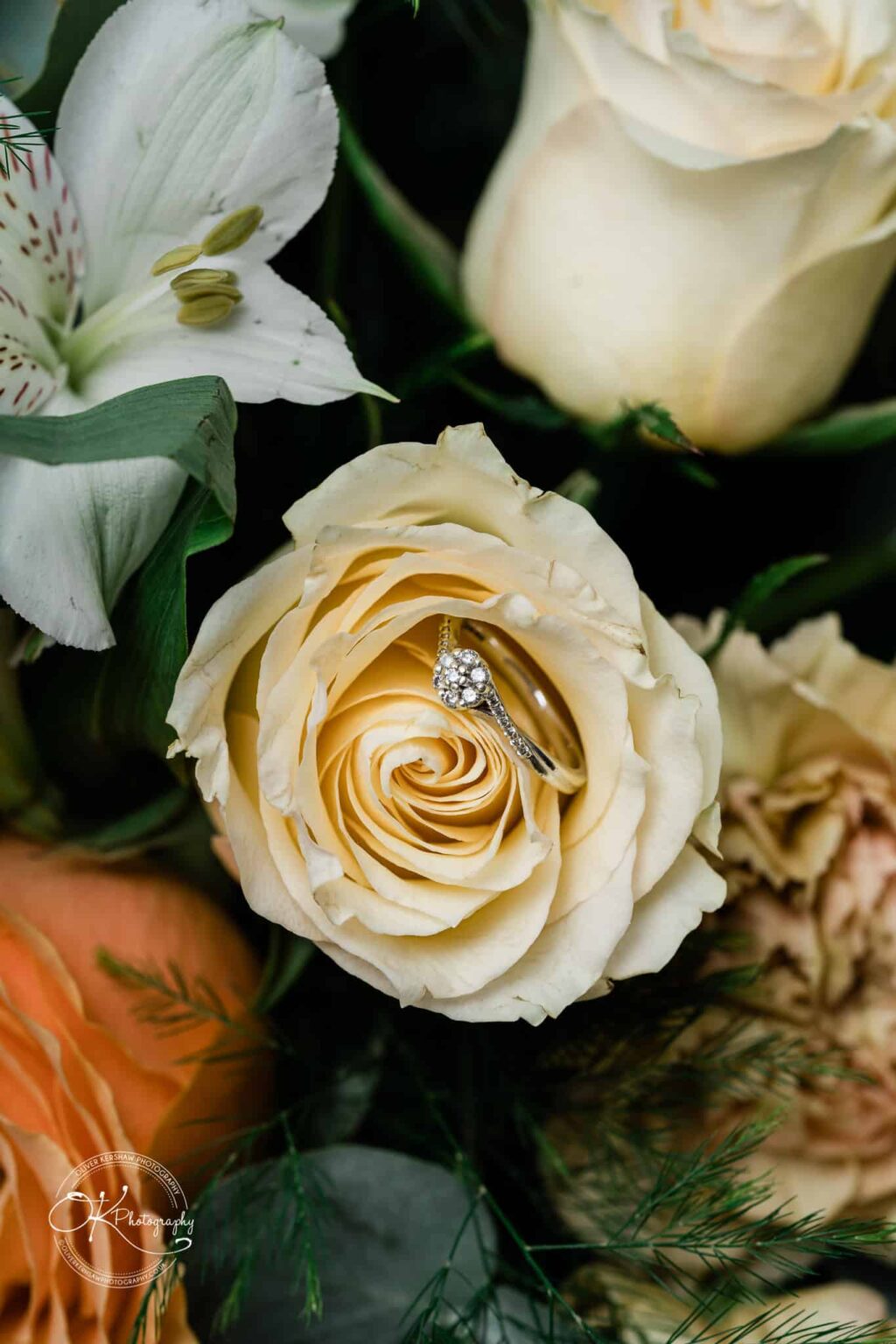 Wedding photography The Embankment Close-up of a diamond ring nestled inside a light yellow rose, with other flowers in the background.