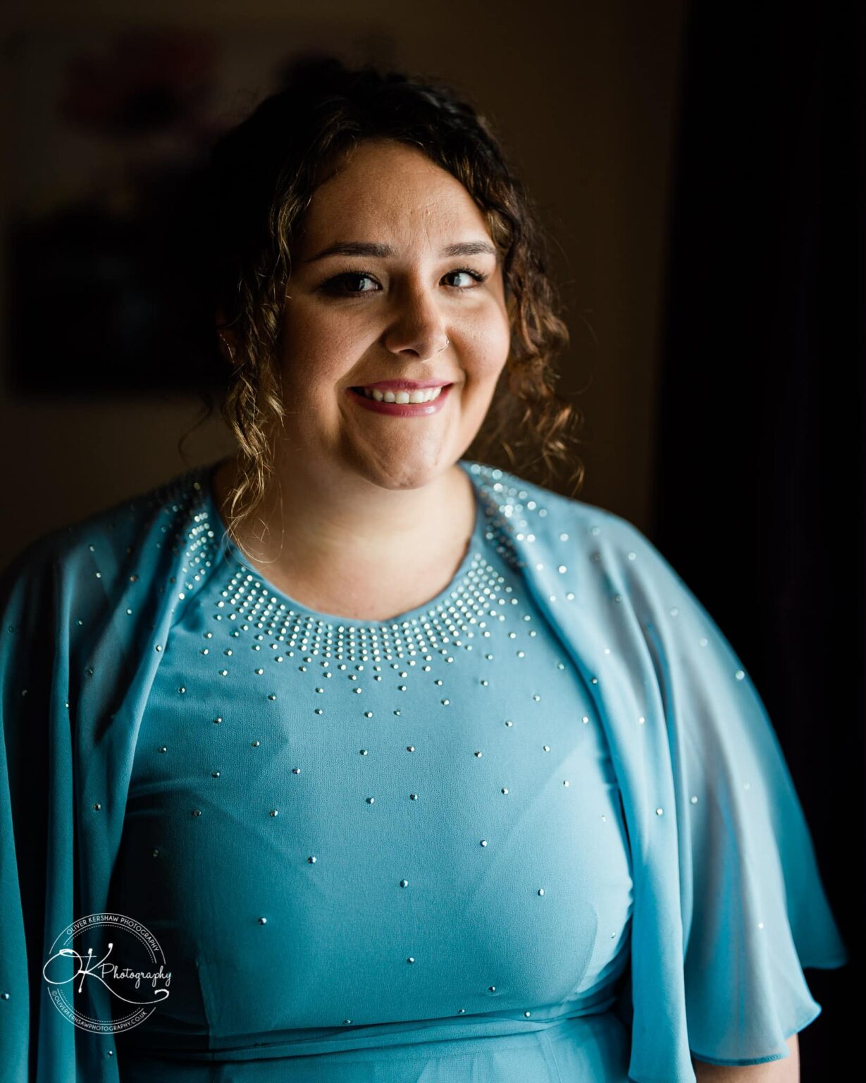 Wedding photography The Embankment Woman in a blue dress with beading, smiling and looking at the camera.