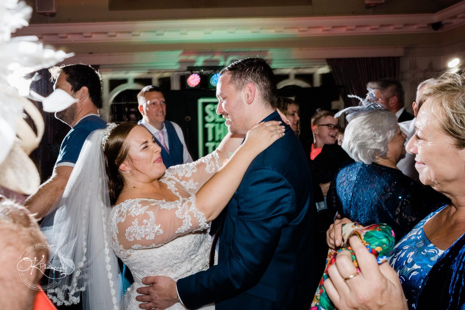 Wedding photography The Embankment A bride and groom dancing closely at their wedding reception, surrounded by smiling guests.