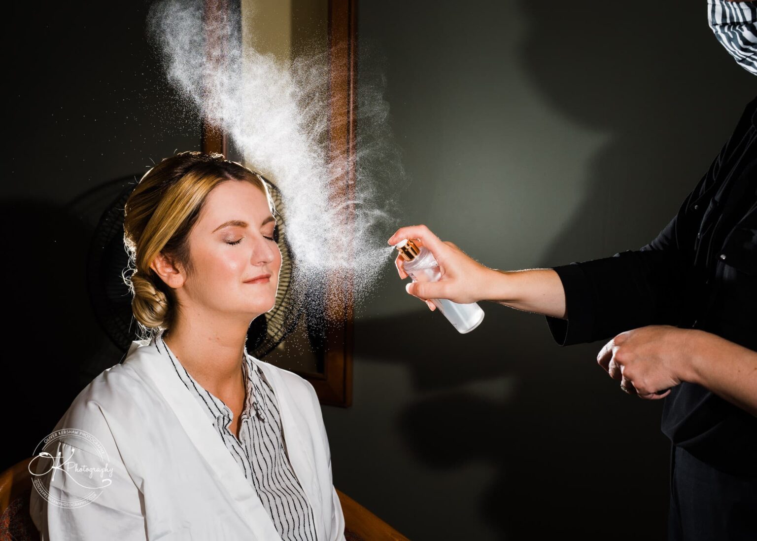Yew Lodge Hotel Wedding Photography A woman getting her makeup set with a spray, eyes closed, in a relaxed pose during wedding preparations.