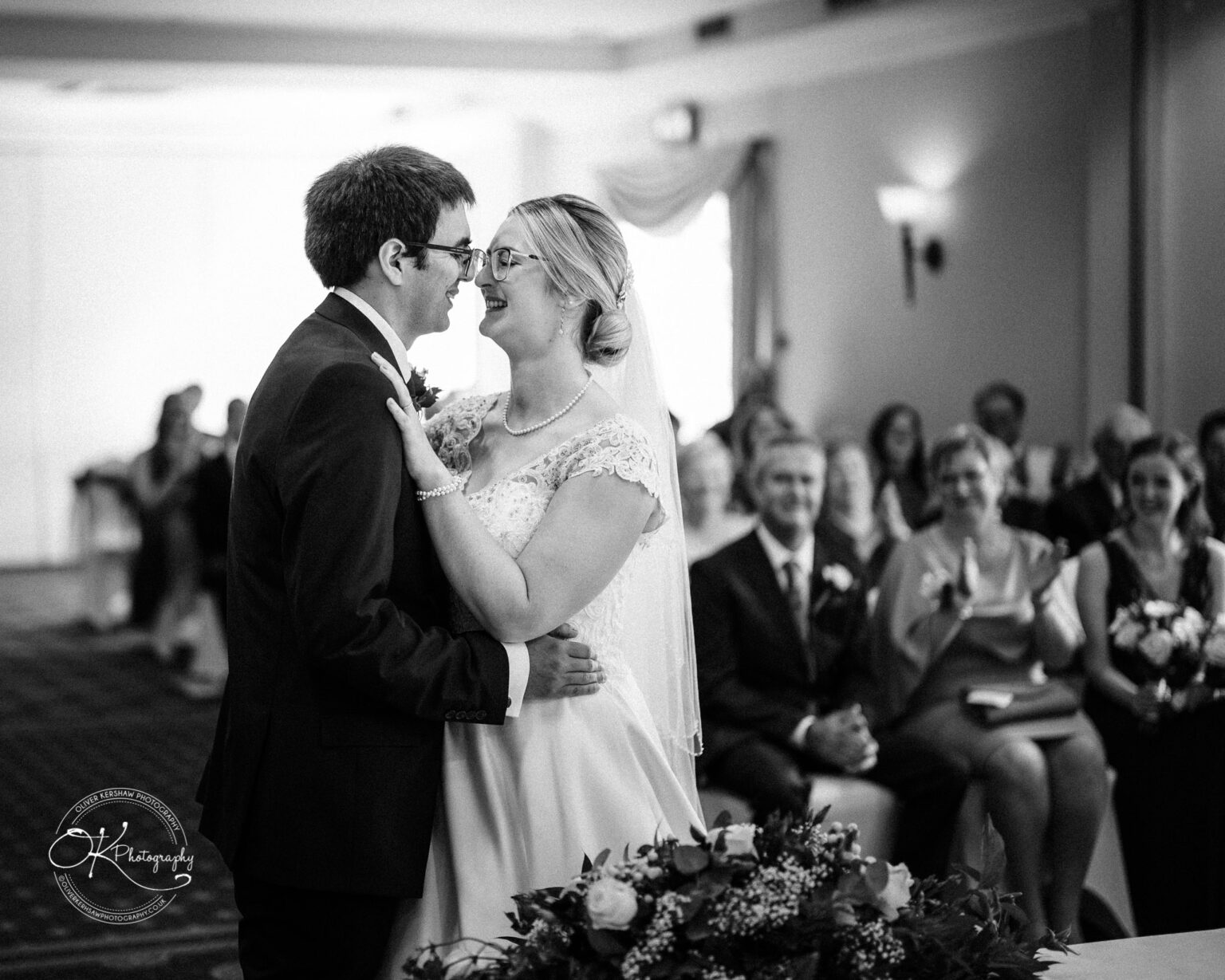 Yew Lodge Hotel Wedding Photography Bride and groom sharing a first dance, surrounded by smiling guests at an indoor wedding reception, Yew Lodge Hotel.