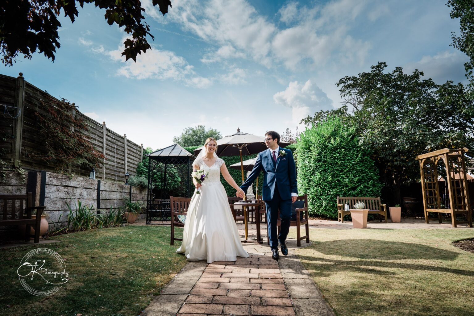 Yew Lodge Hotel Wedding Photography Bride and groom holding hands and walking in a garden at Yew Lodge Hotel.