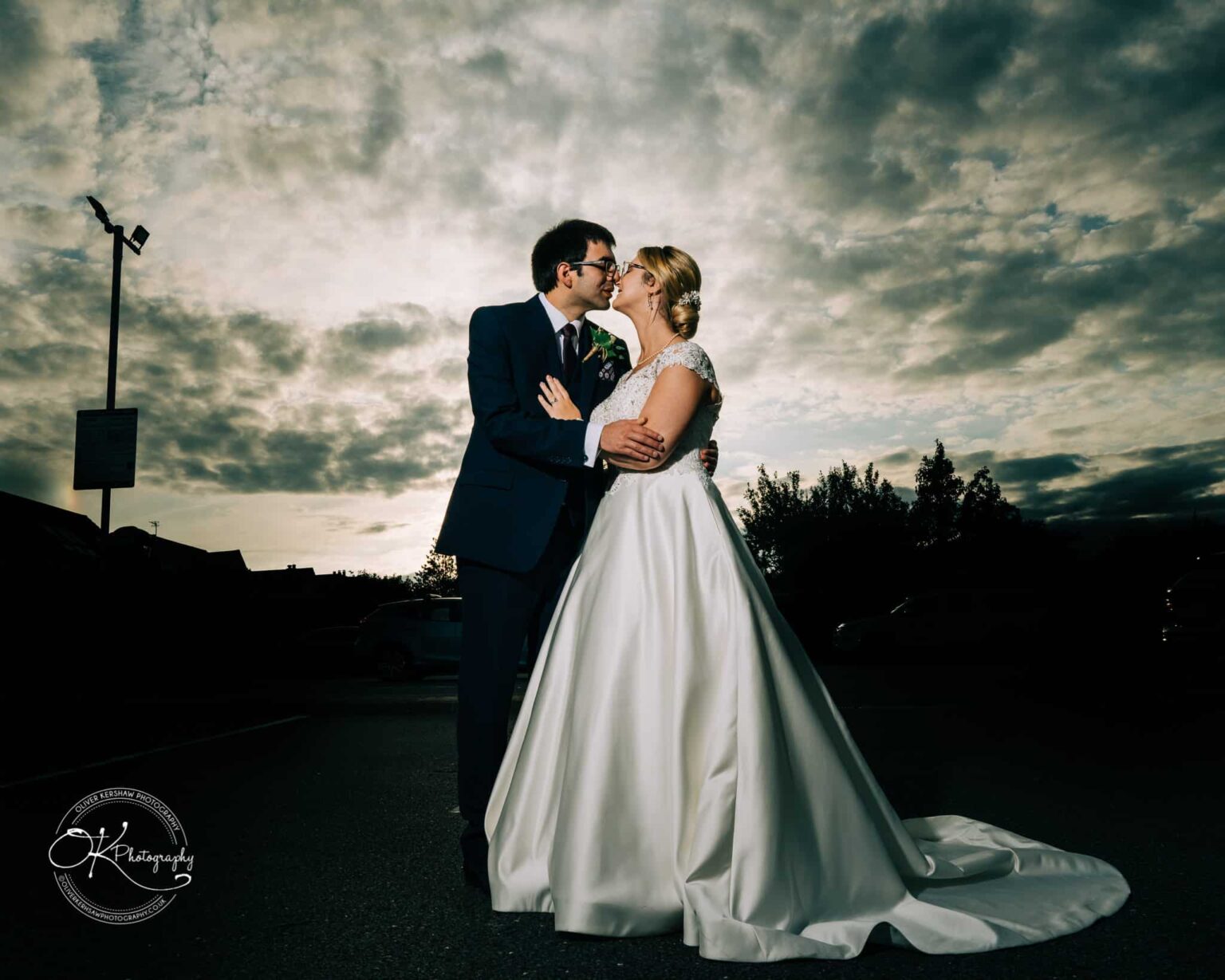 Yew Lodge Hotel Wedding Photography Bride and groom embracing under a dramatic sky.