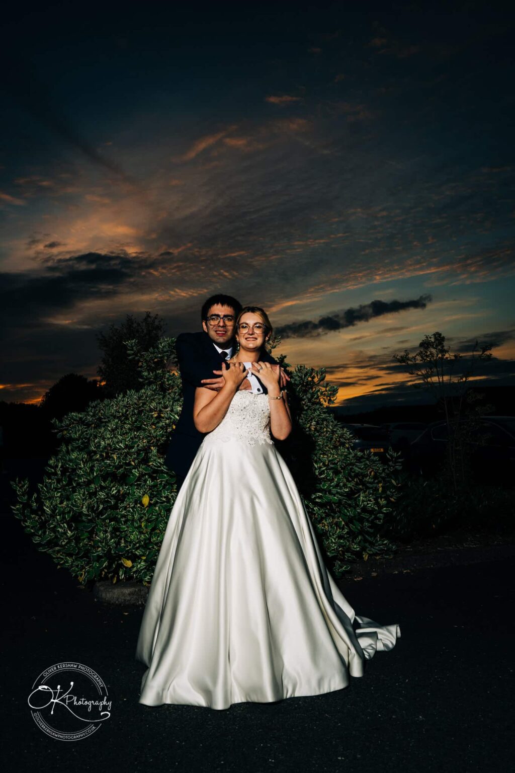 Yew Lodge Hotel Wedding Photography Bride and groom at sunset, with bride in a white gown and groom in a dark suit.