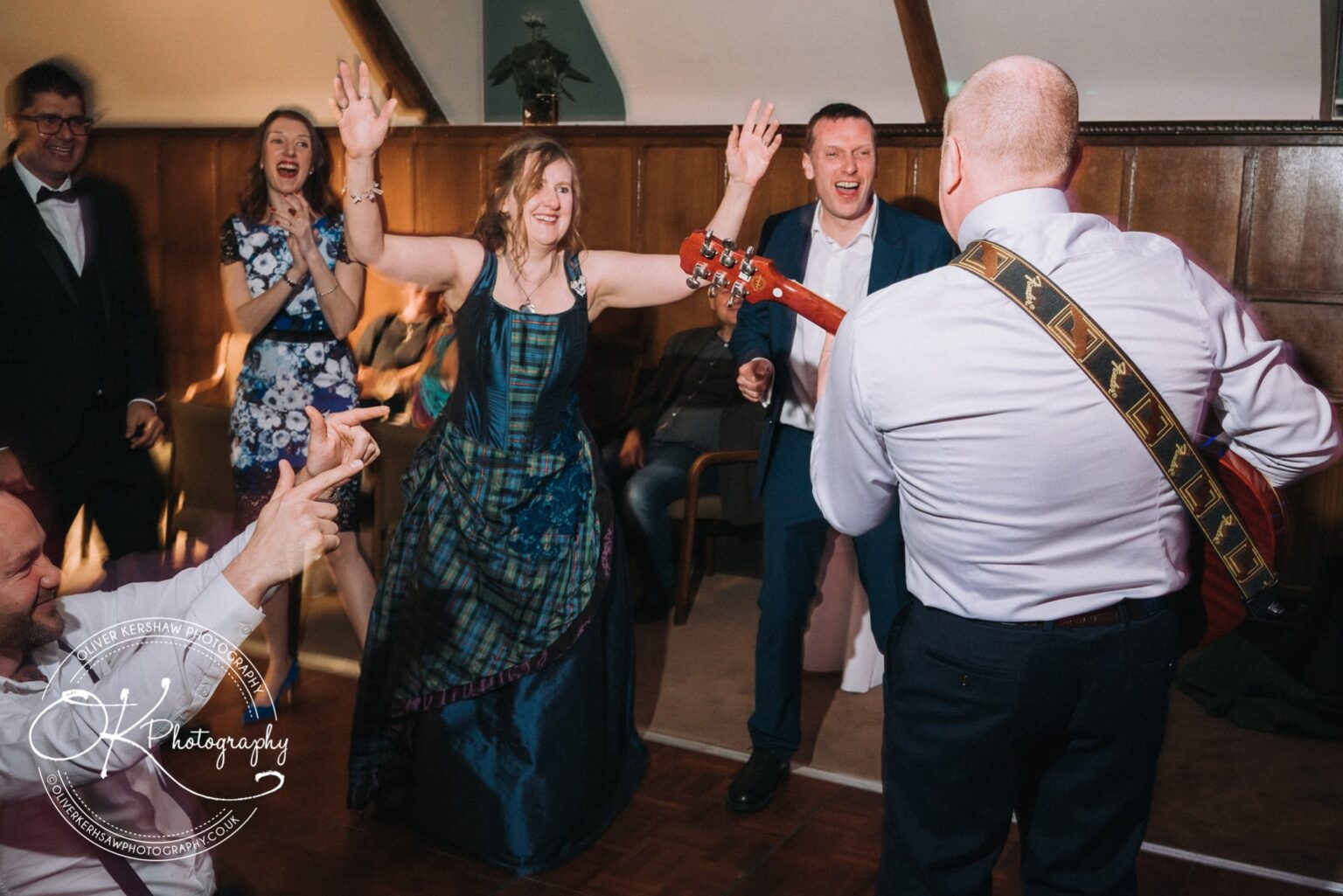 Wedding Photography George Hotel Stamford A group of people dancing joyfully, with a man playing guitar in the foreground.