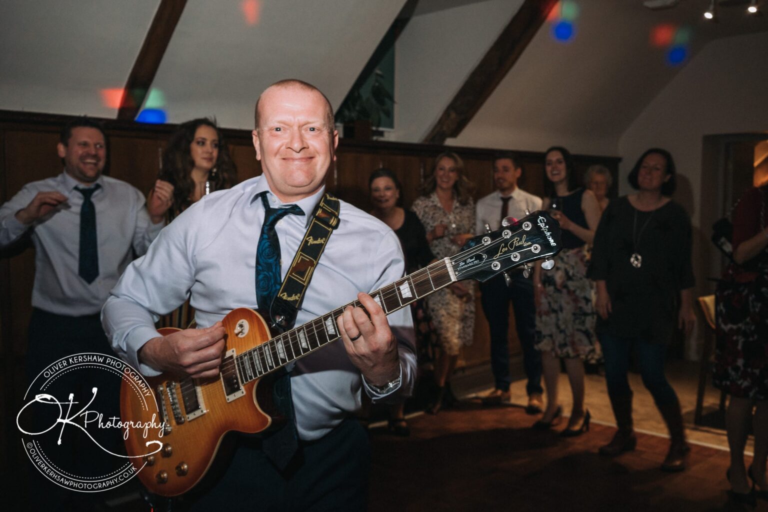 Wedding Photography George Hotel Stamford A man playing an electric guitar in front of a group of people dancing and watching, at George Hotel Stamford.
