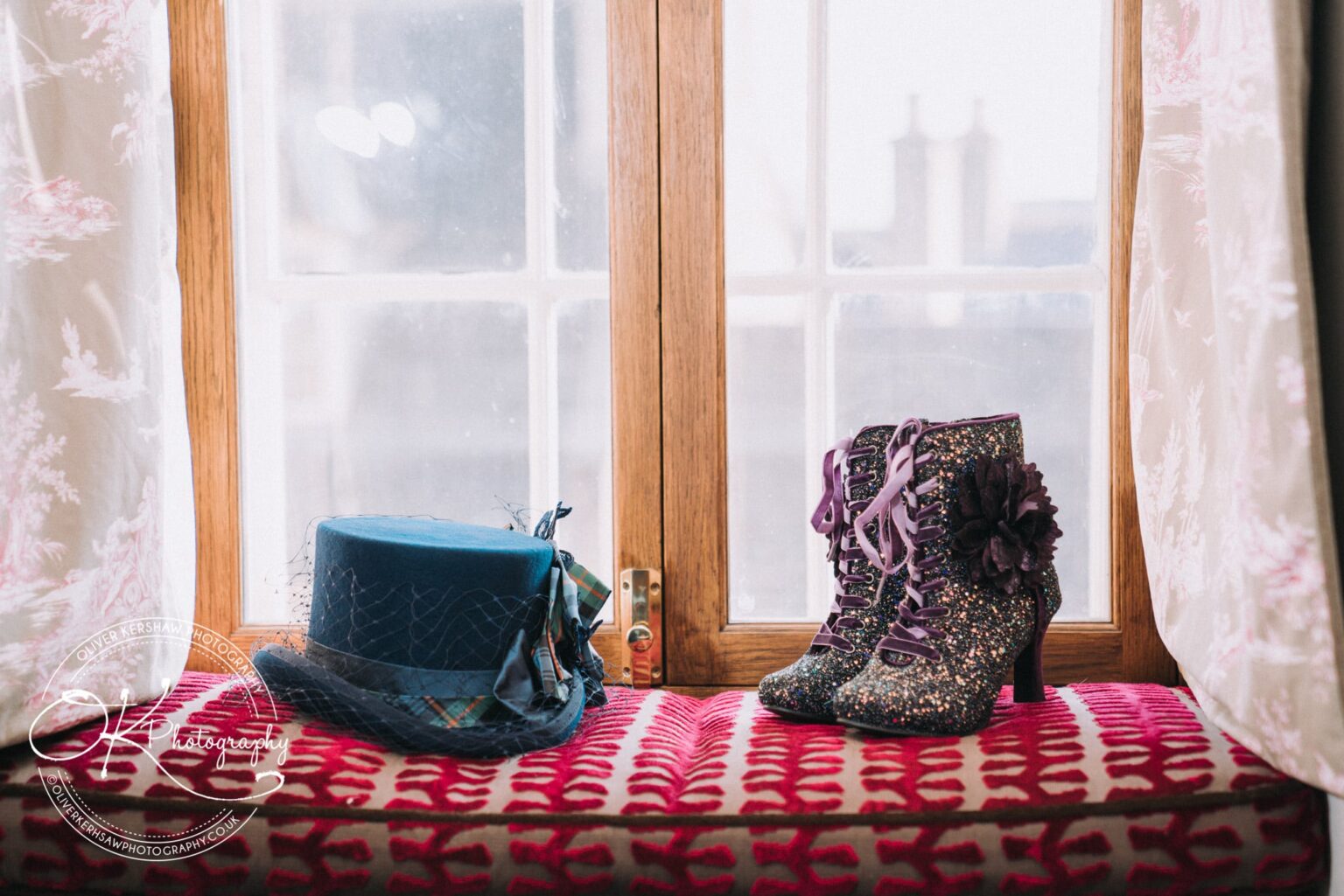 Wedding Photography George Hotel Stamford A blue hat with netting and a pair of sequined boots with purple laces placed on a cushioned window seat next to a wooden window frame.