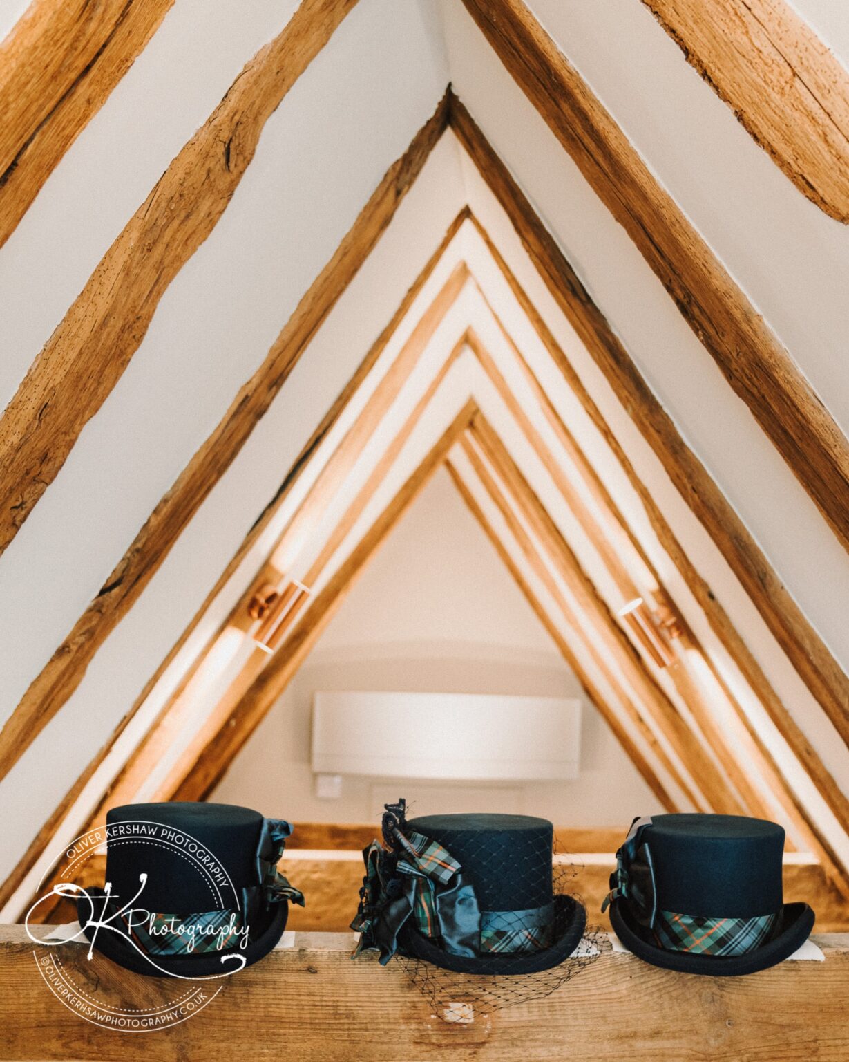 Wedding Photography George Hotel Stamford Three black top hats with tartan ribbons on a wooden beam, inside a rustic room with exposed wooden beams on the ceiling.