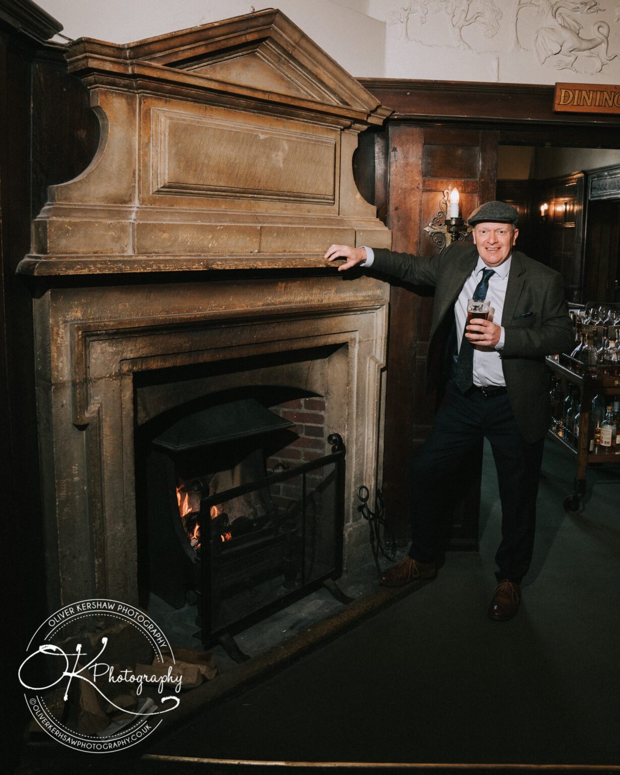 Wedding Photography George Hotel Stamford A man holding a drink standing by a fireplace at the George Hotel in Stamford.