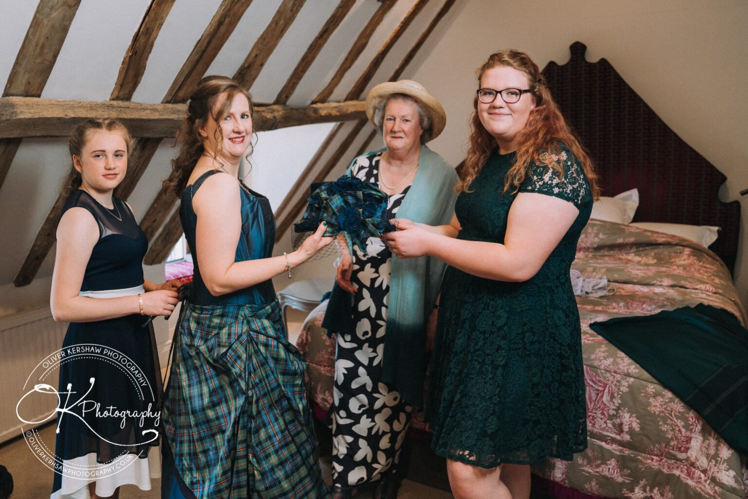 Wedding Photography George Hotel Stamford Four women in formal attire, standing together in a room with exposed wooden beams and a bed in the background.