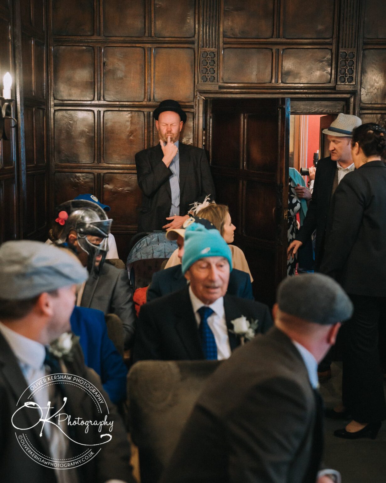 Wedding Photography George Hotel Stamford A group of people in suits and hats gathered in a paneled room.